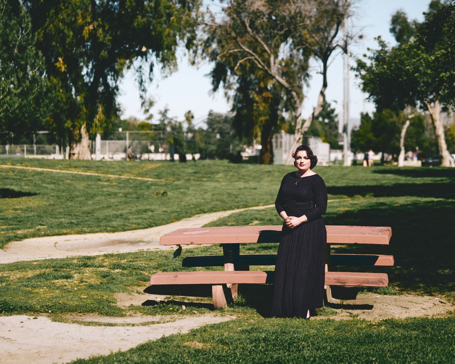 Four wooden benches arranged geometrically on a grassy slope in a peaceful park setting.