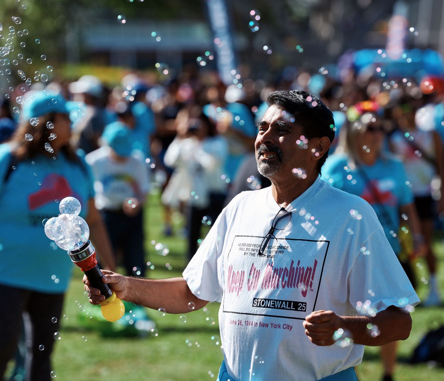 Soap bubbles float through the air at an outdoor summer festival while people enjoy the sunny day.