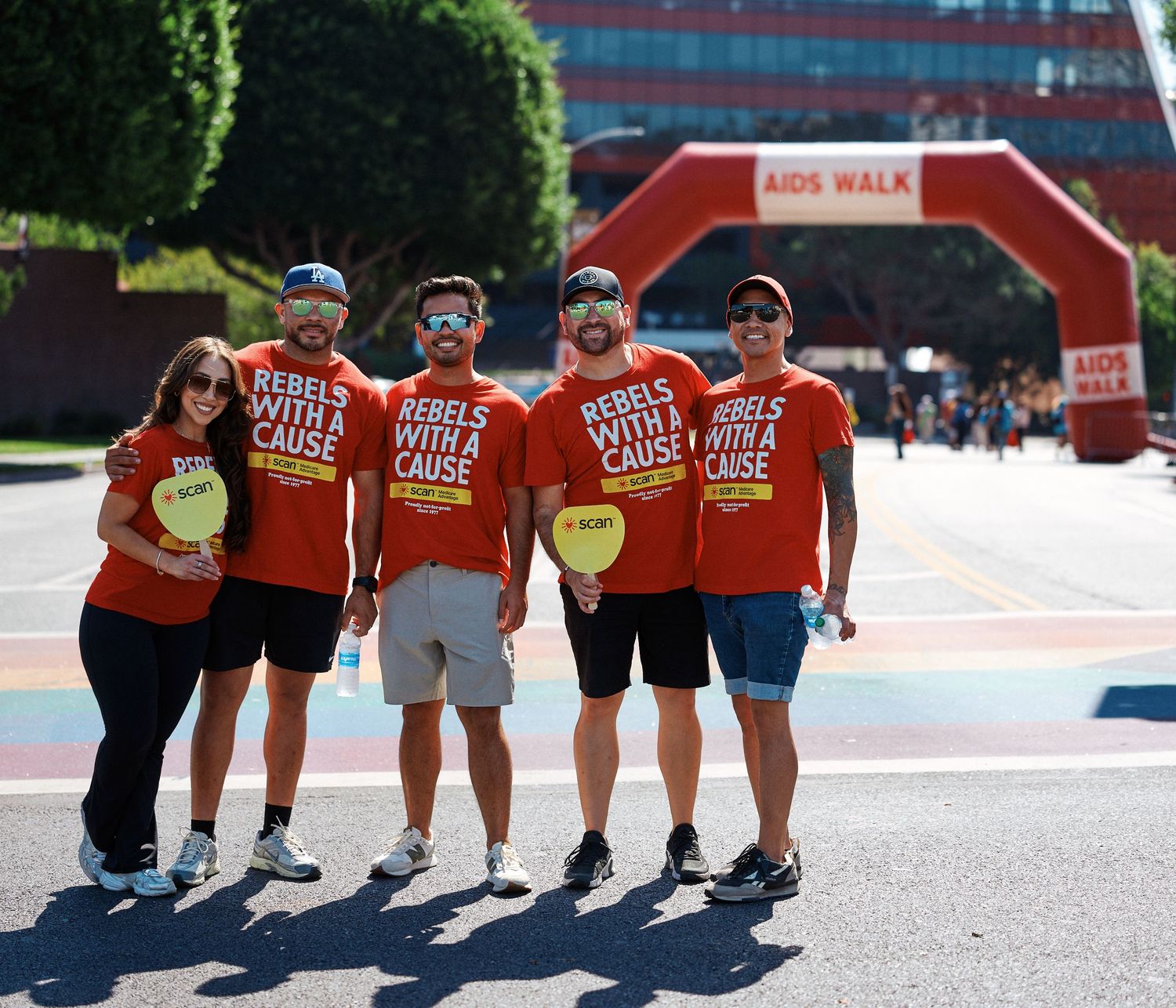 A group wearing matching orange t-shirts poses together at a charity walk event.