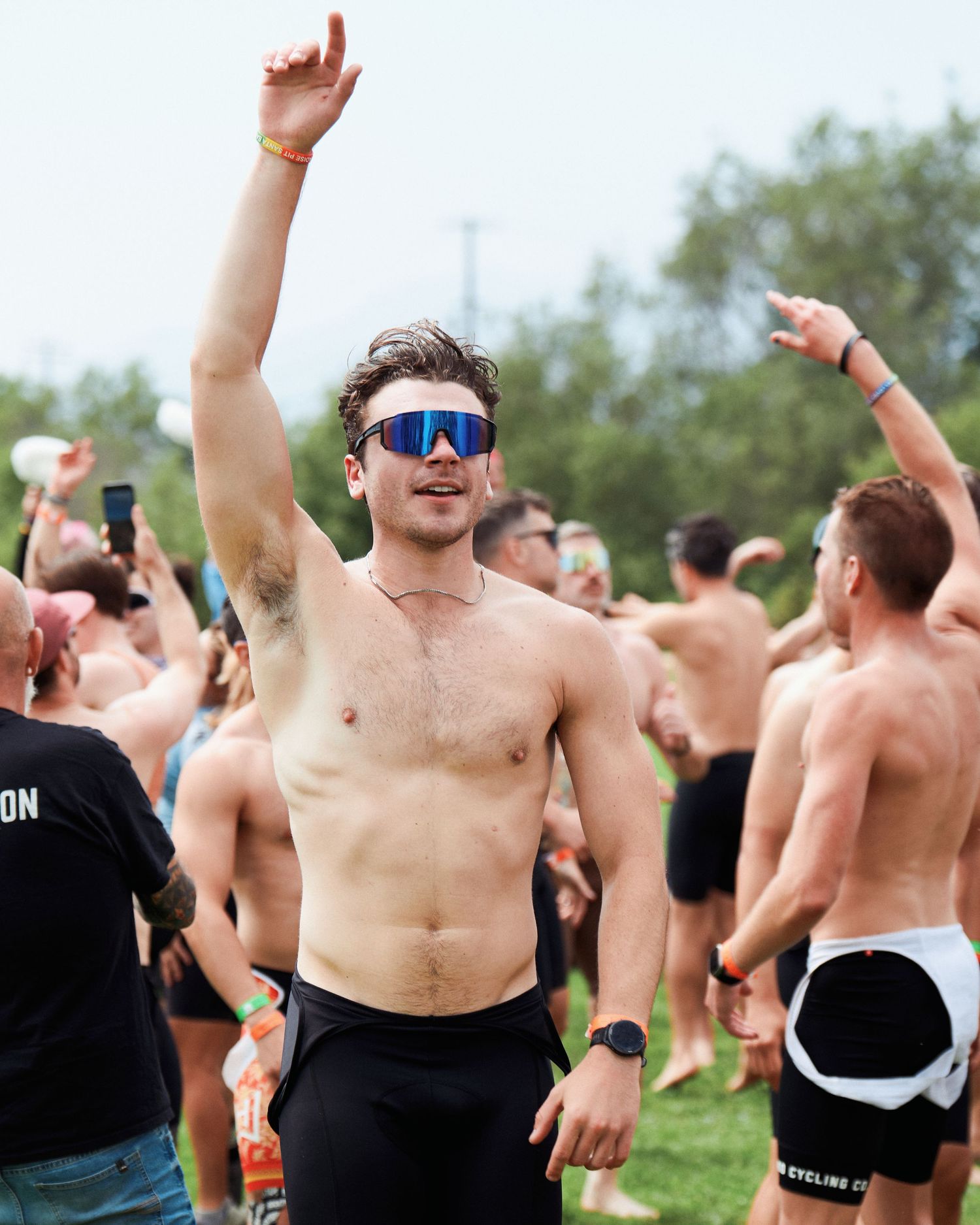 Crowd of energetic participants celebrating with raised arms at an outdoor fitness event.