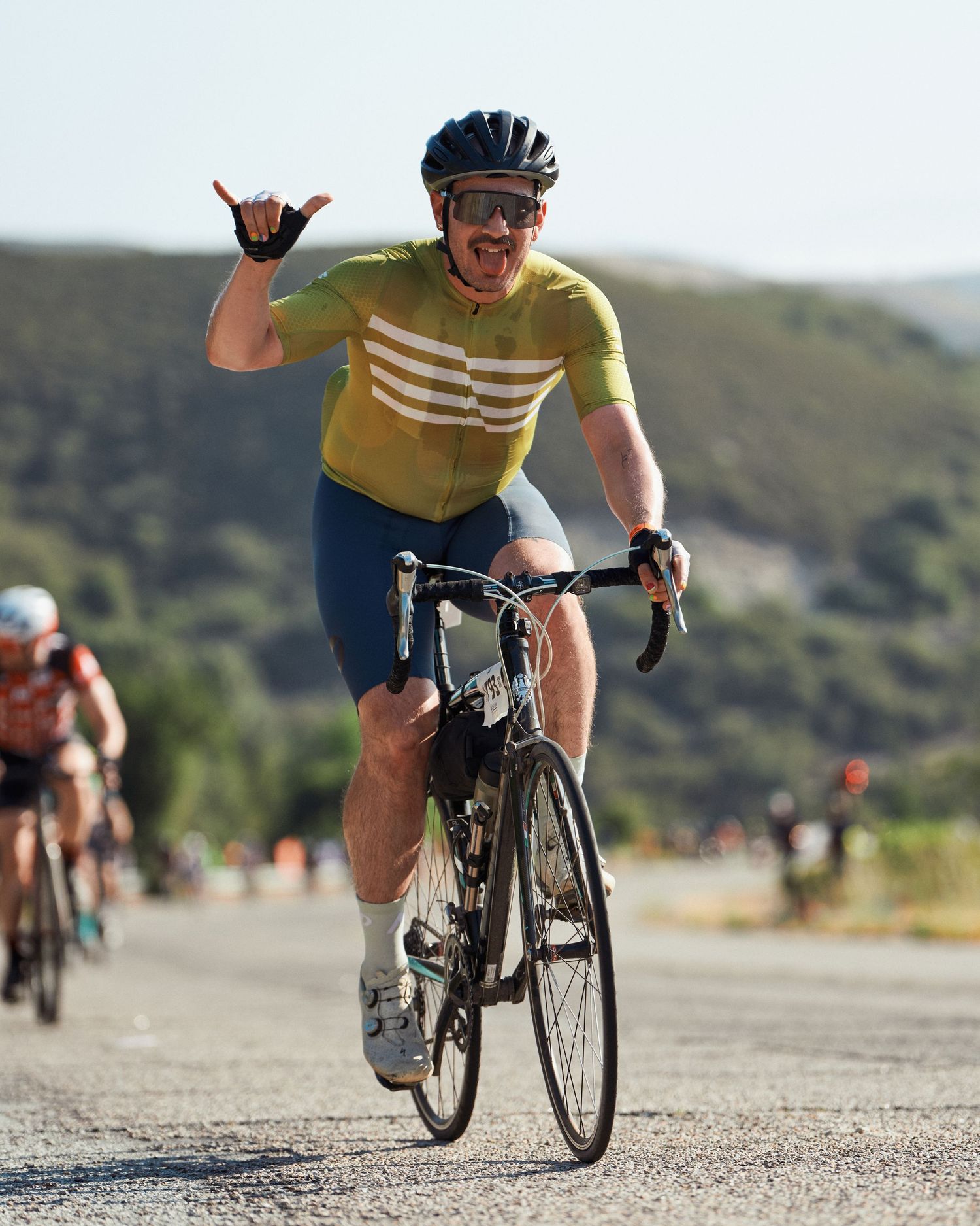 Cyclist in yellow jersey riding on a road with black bike shown across multiple action shots of the same sequence.