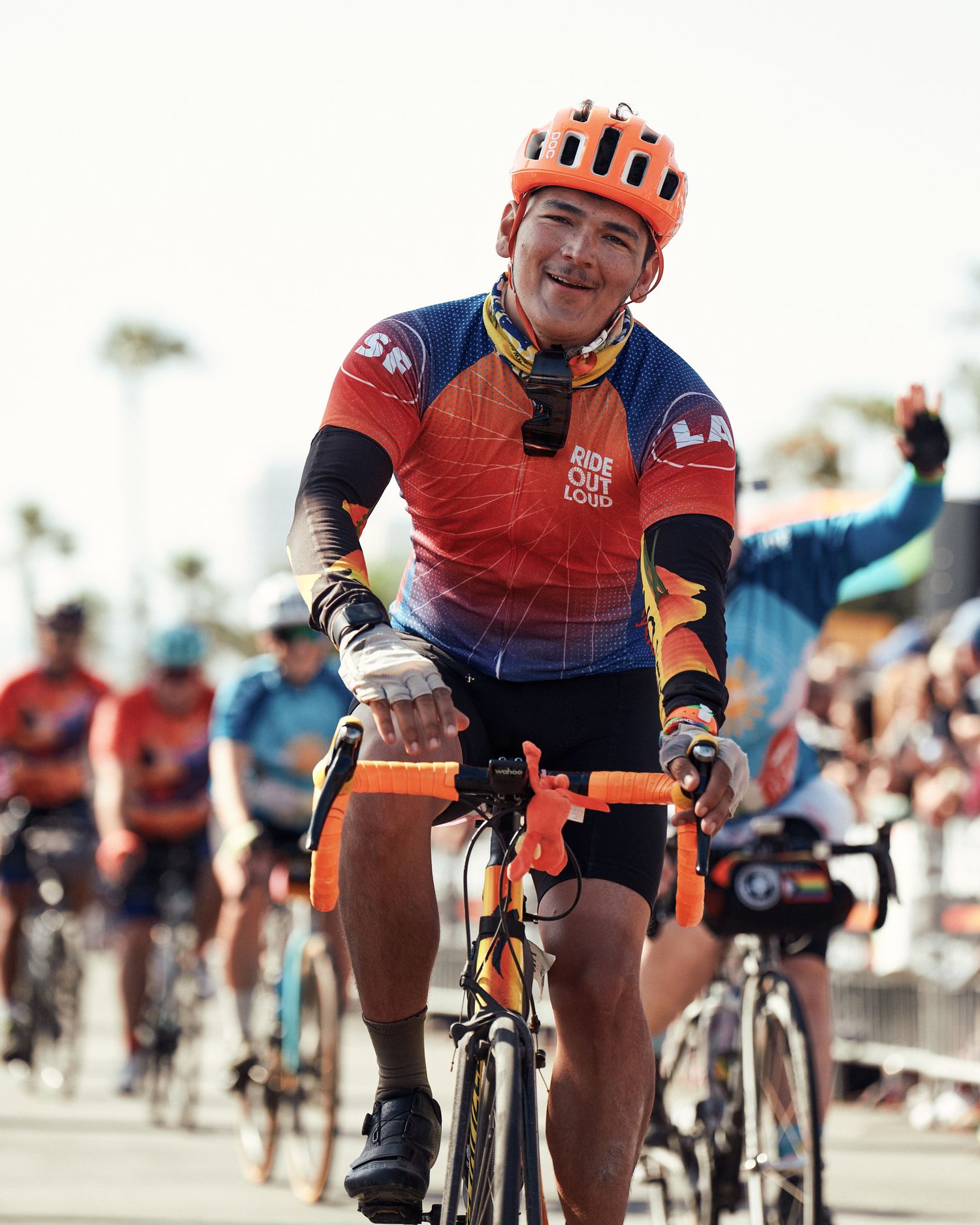 Closeup of riders in orange and blue cycling jerseys racing in a group formation.