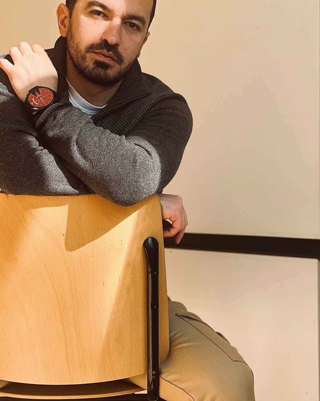 portrait of a man sitting on a chair posing for the camera with e shadow on