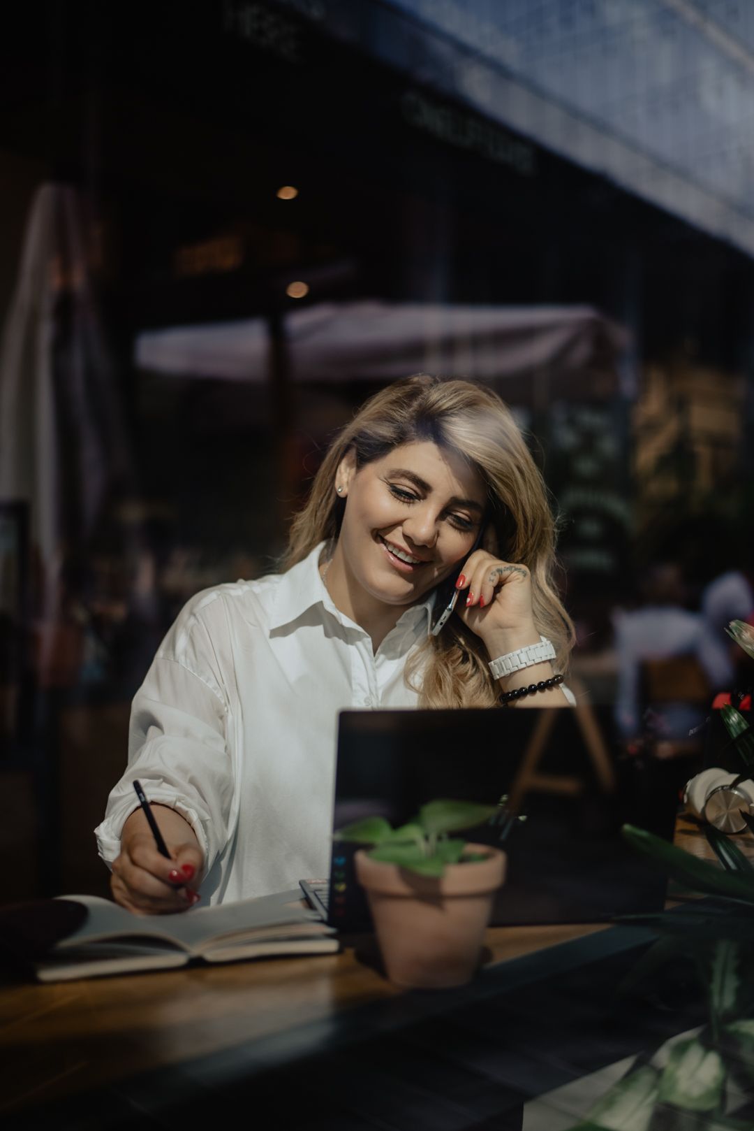 a business woman portrait shot talking on the phone and working on laptop in an counter working environment