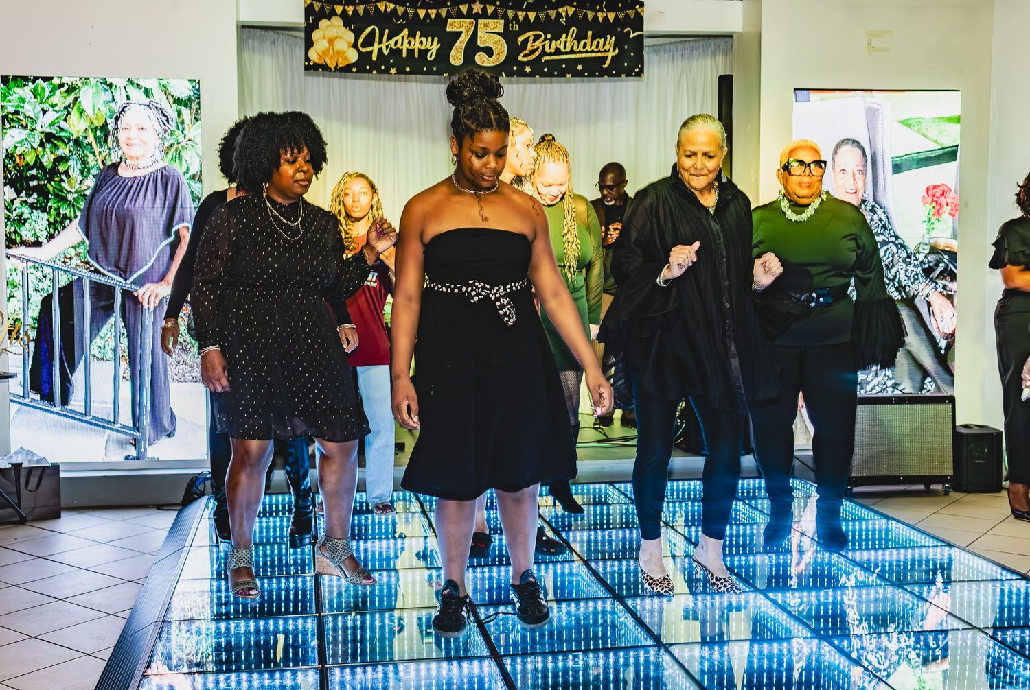 Group of women dancing on illuminated LED dance floor at a 75th birthday celebration party.