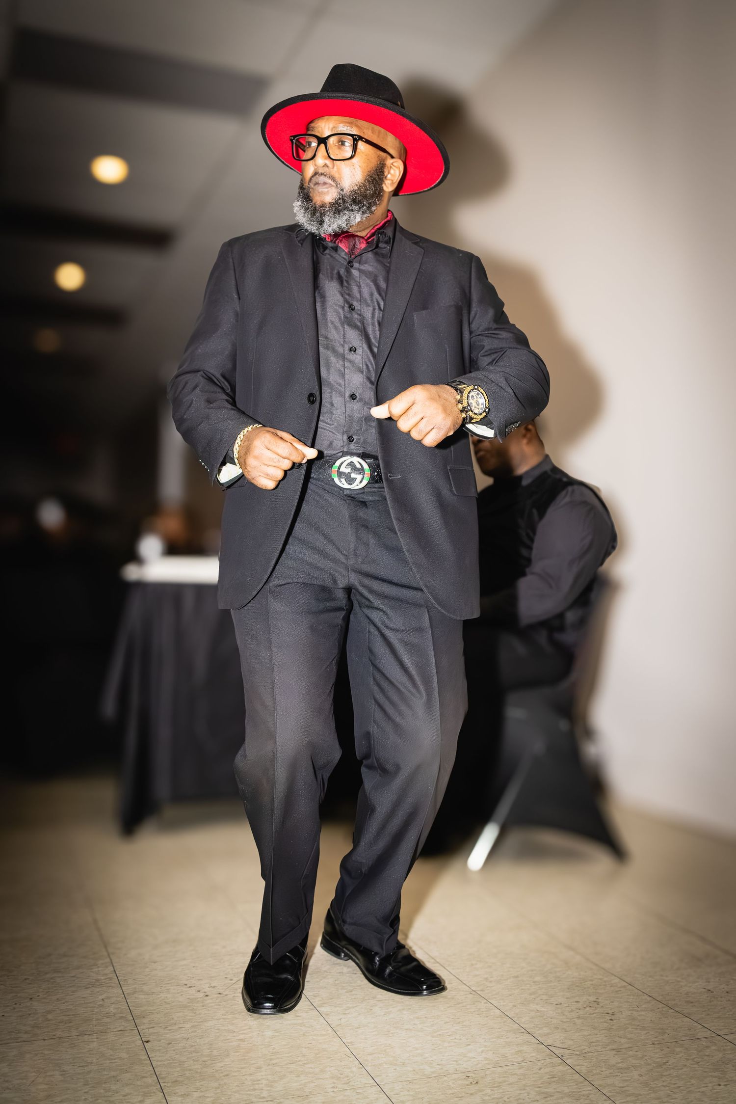 Dapper suit ensemble with red fedora and bowtie creating a striking formal look.