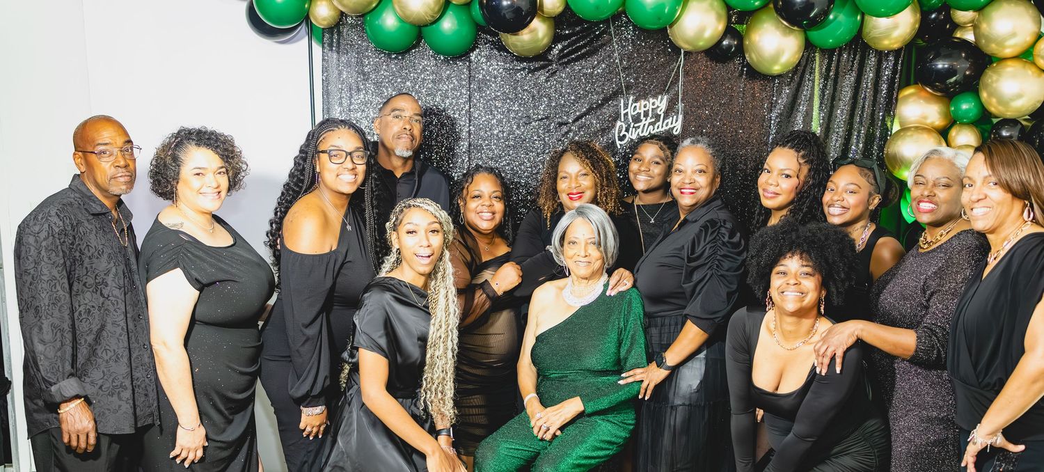 People in black and green attire gather at a social event with festive holiday decorations and ornaments.
