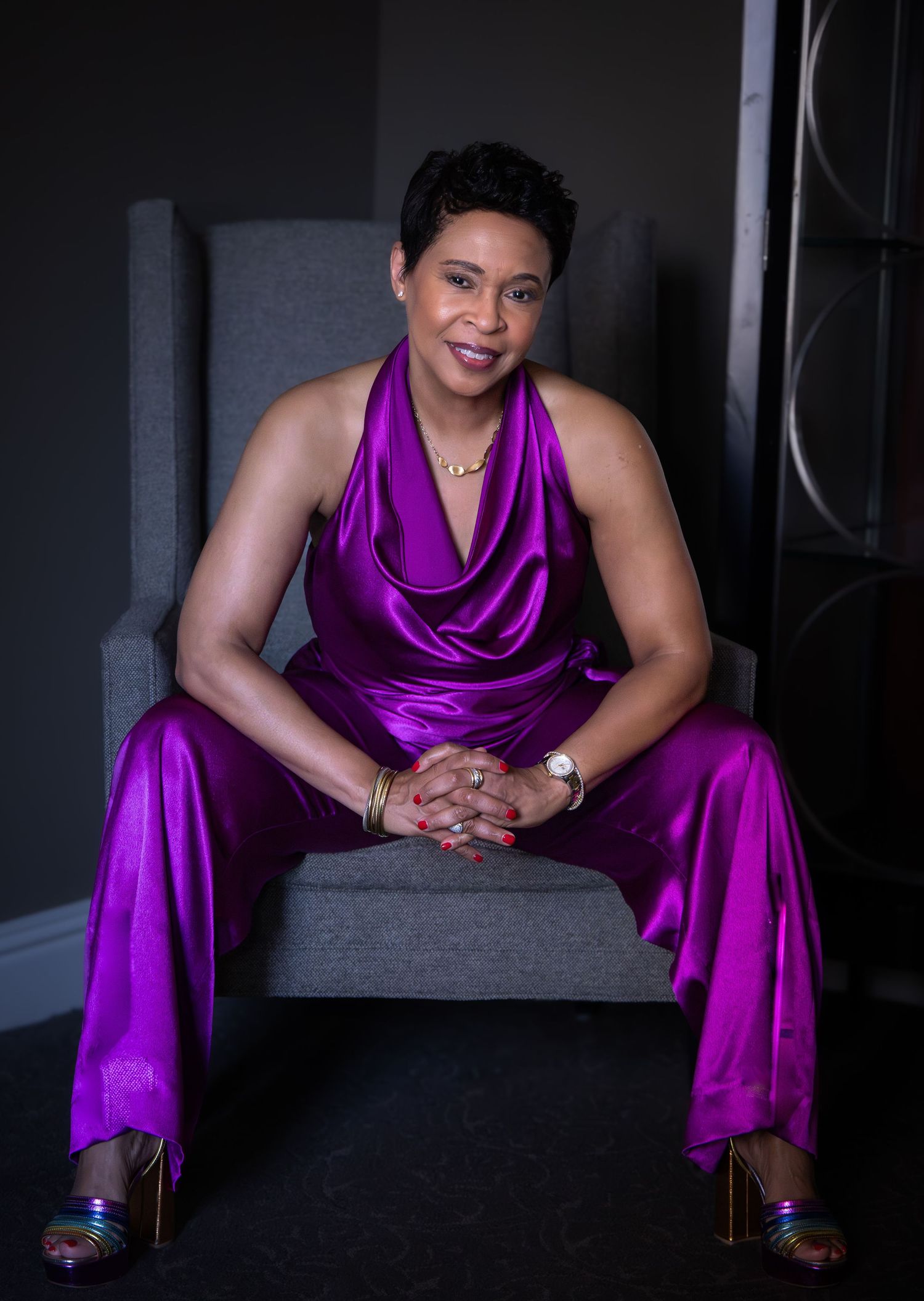 A series of photos showing someone in a vibrant purple satin dress seated on dark steps in dramatic lighting.