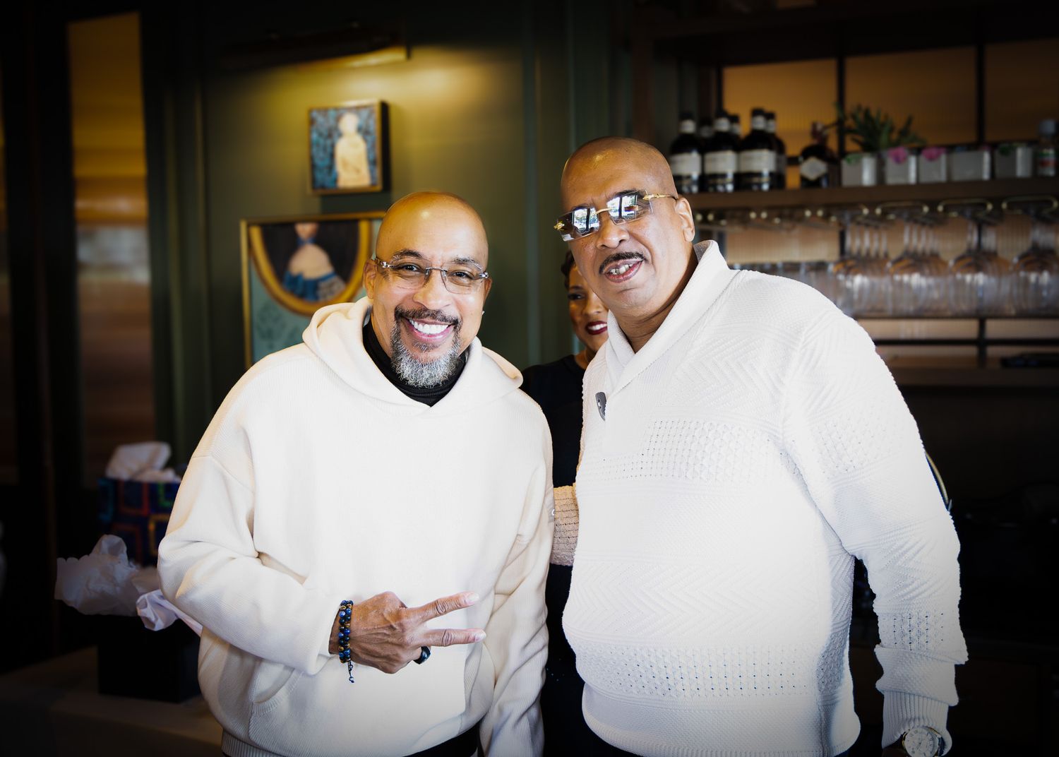A series of four connected photos showing two people in white chef coats greeting and embracing each other warmly.
