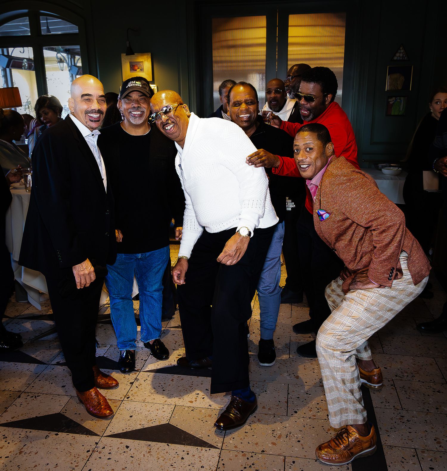 Group of friends laughing and posing together at a casual indoor social gathering.
