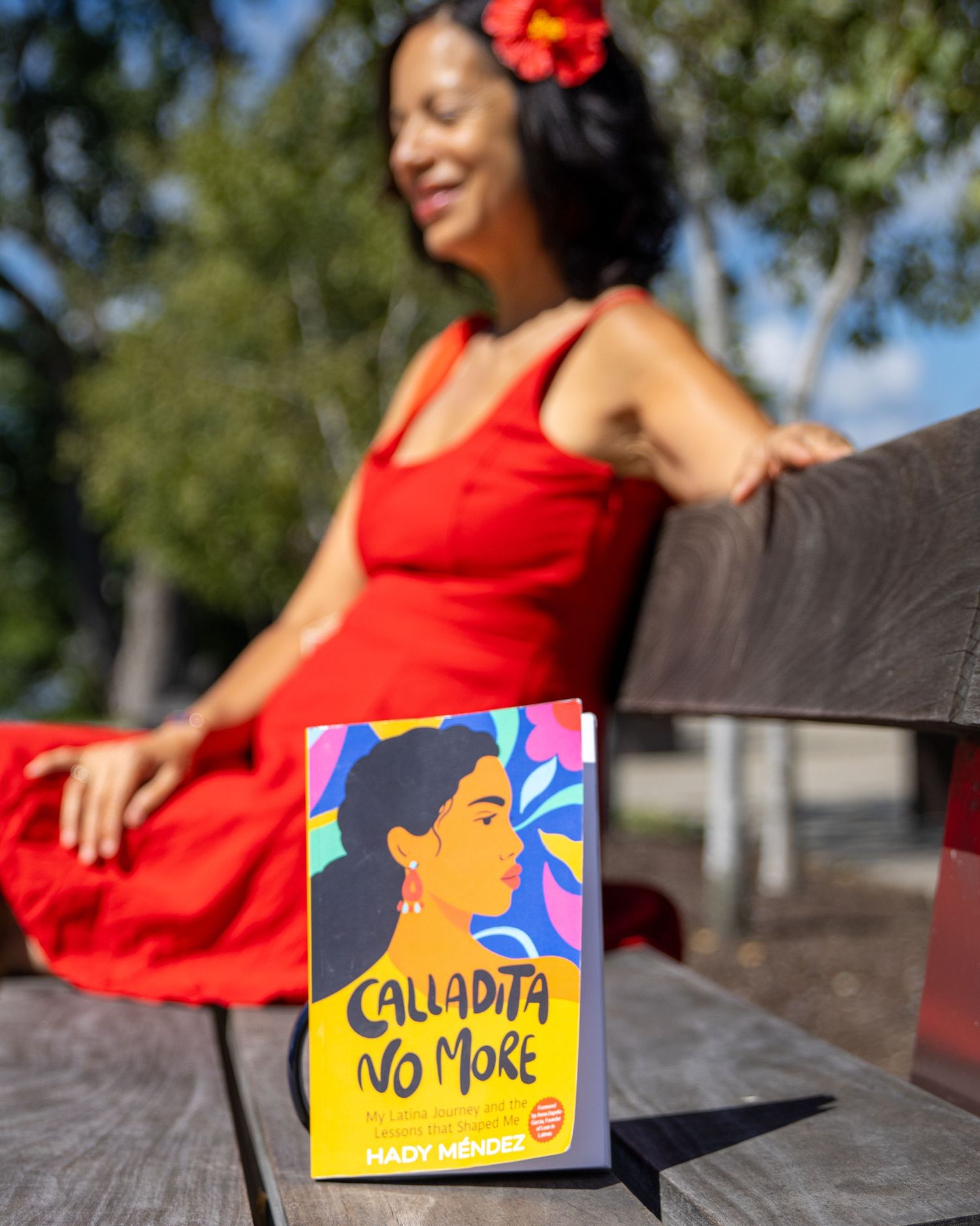Red dress figure with children's book covers displayed on outdoor bench.