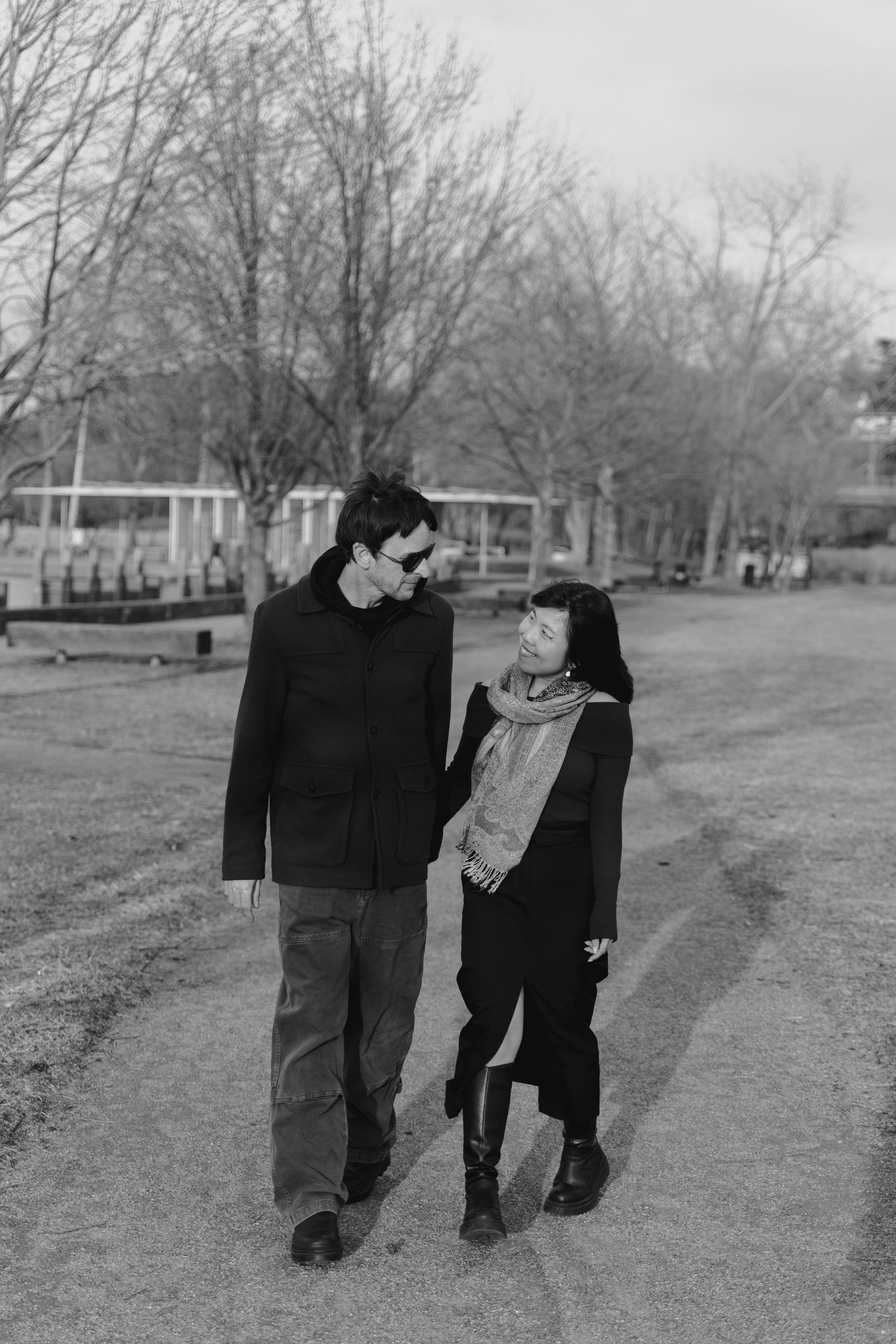 Black and white photo of people walking together on a tree-lined path.