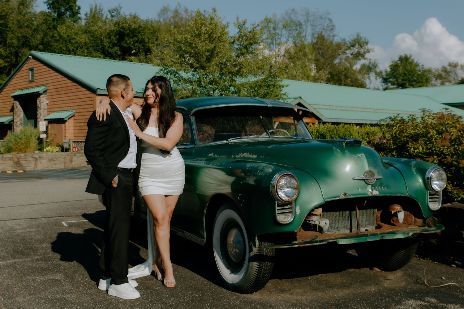 A man and woman holding each other while standing next to a green vintage car at The Barn at Twiggys. Shot at The Barn at Twiggys in Middlet