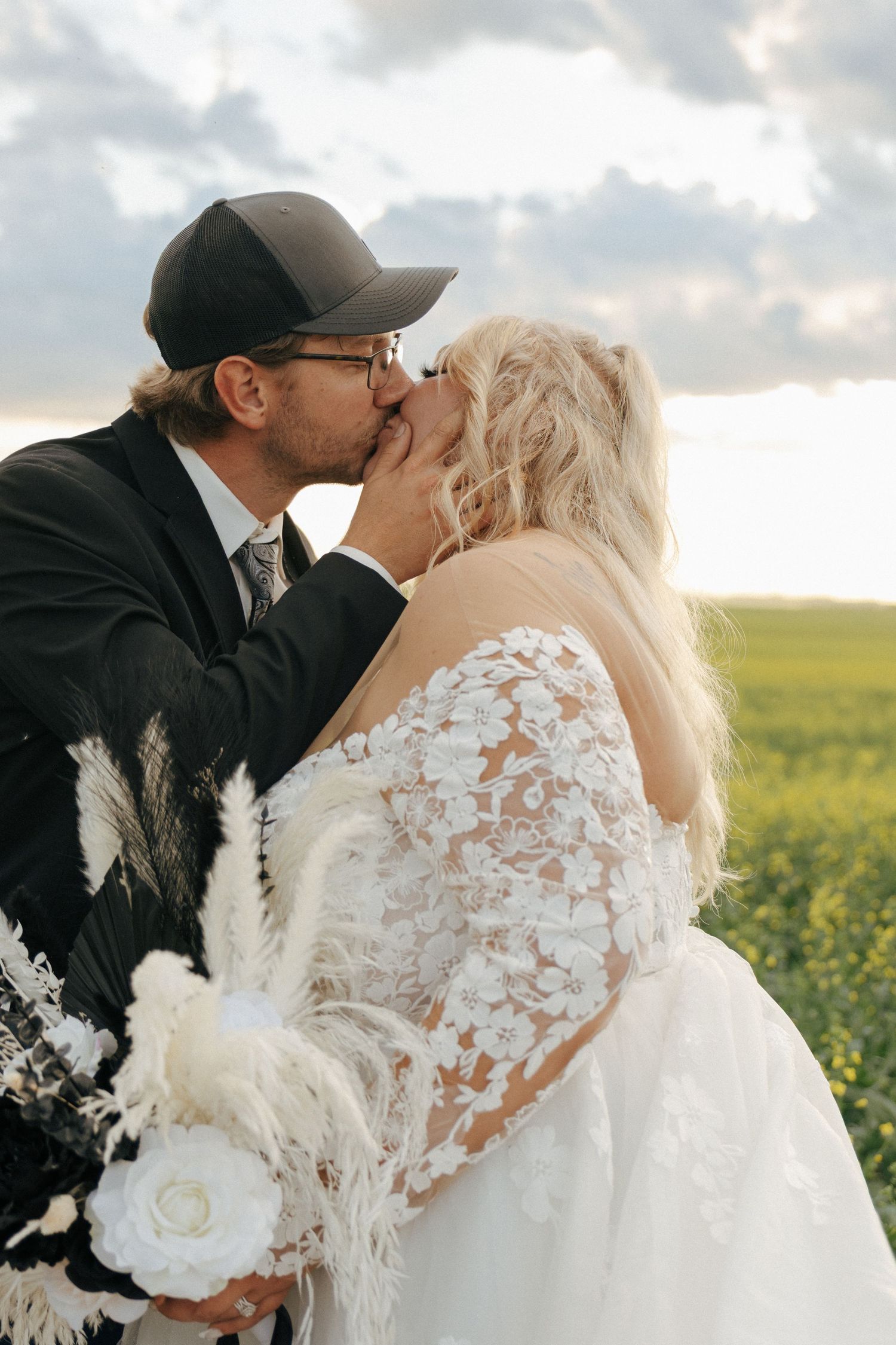 A romantic wedding couple embracing in a sunlit field of yellow flowers.
