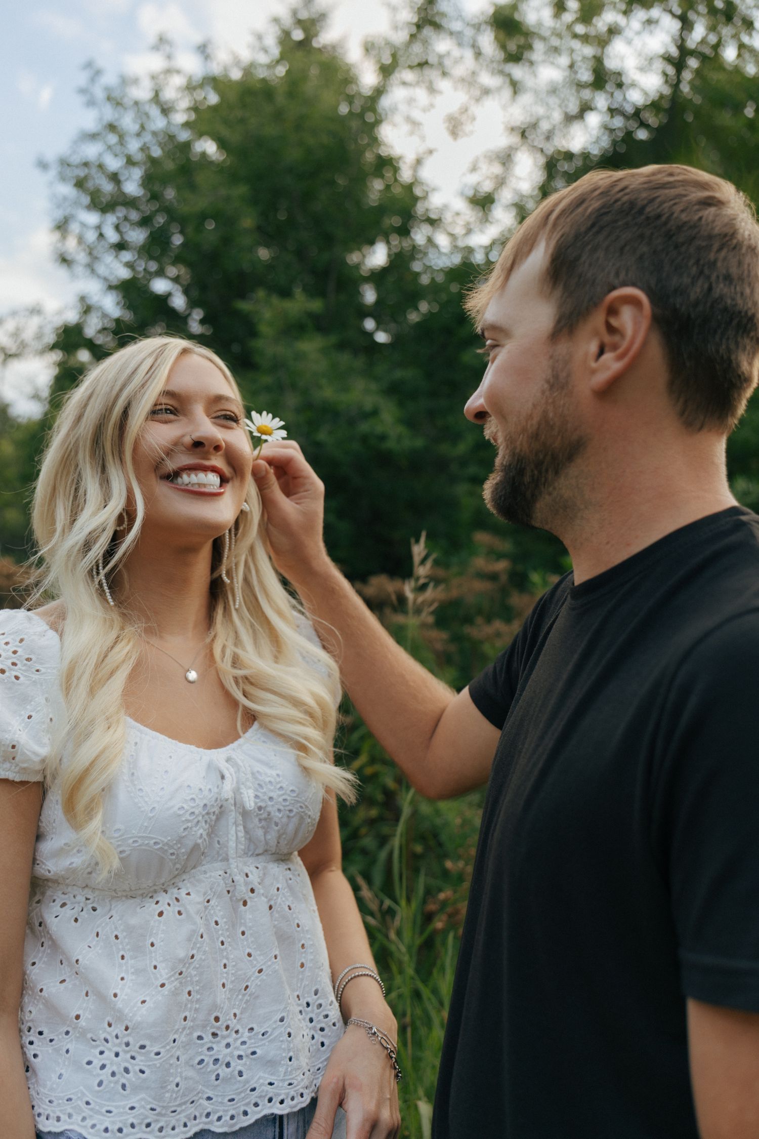 A couple shares playful moments outdoors wearing black and white eyelet dress.