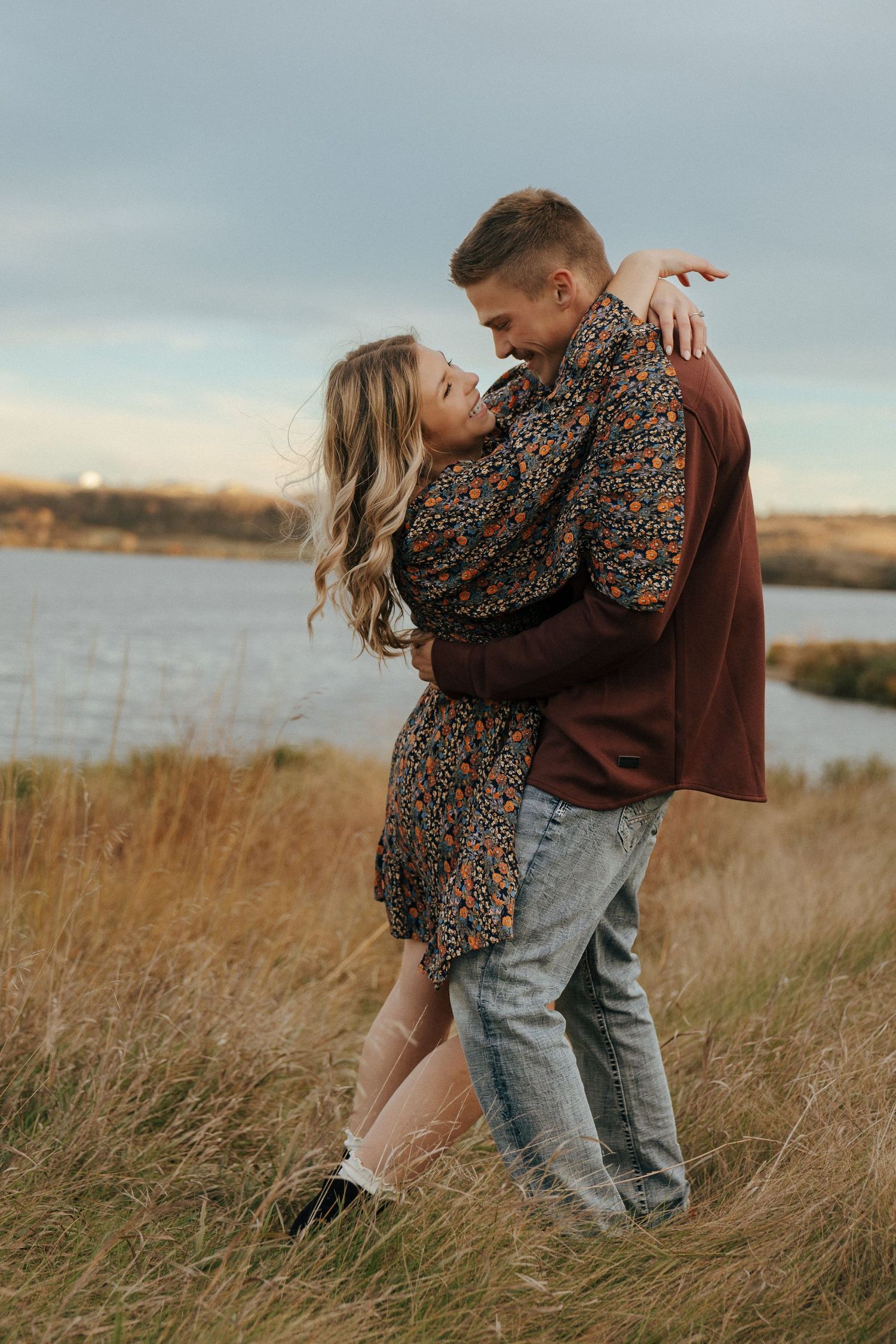 A couple shares an intimate moment in golden light against a natural landscape.