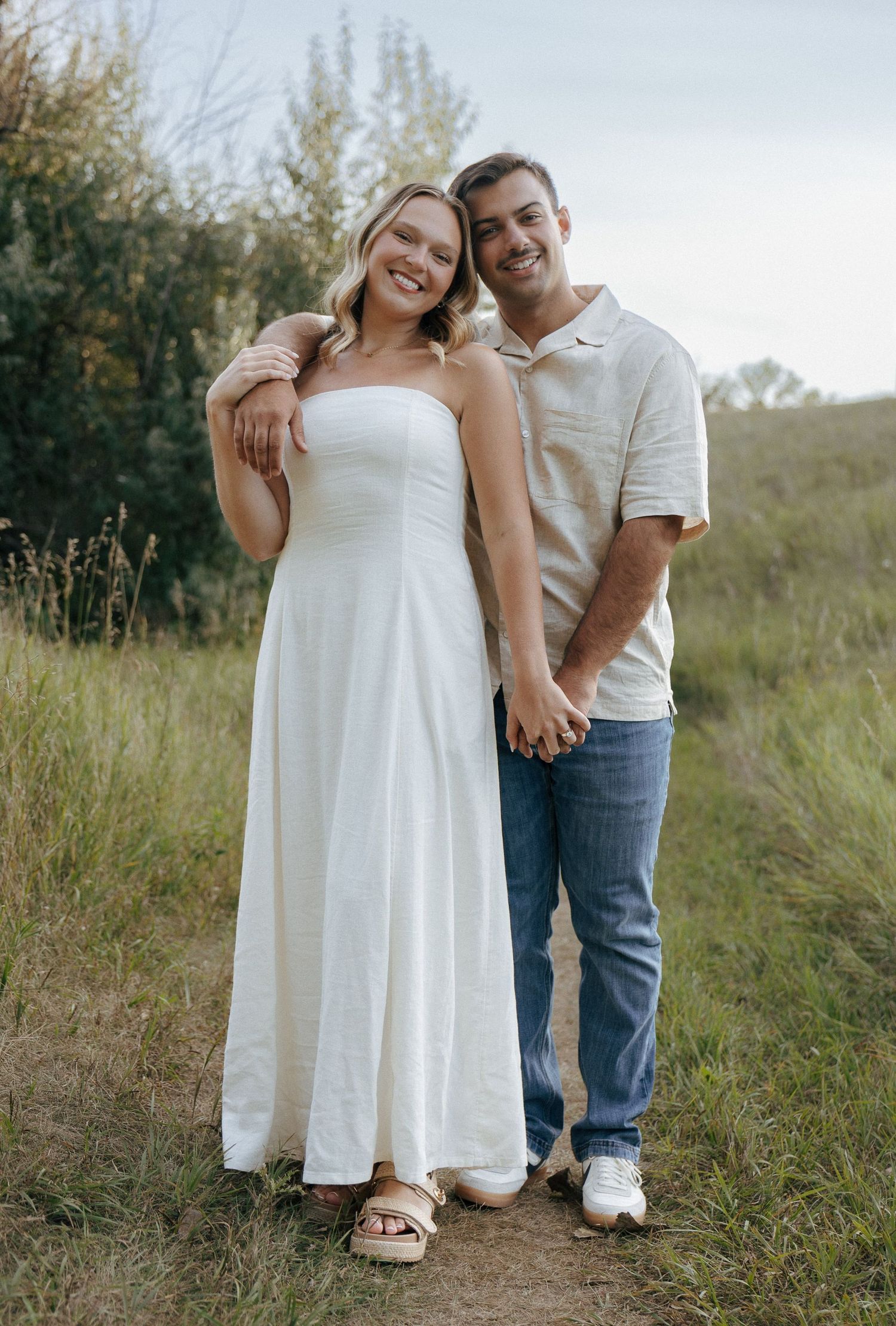 A couple shares a joyful moment together while posing on an outdoor trail.