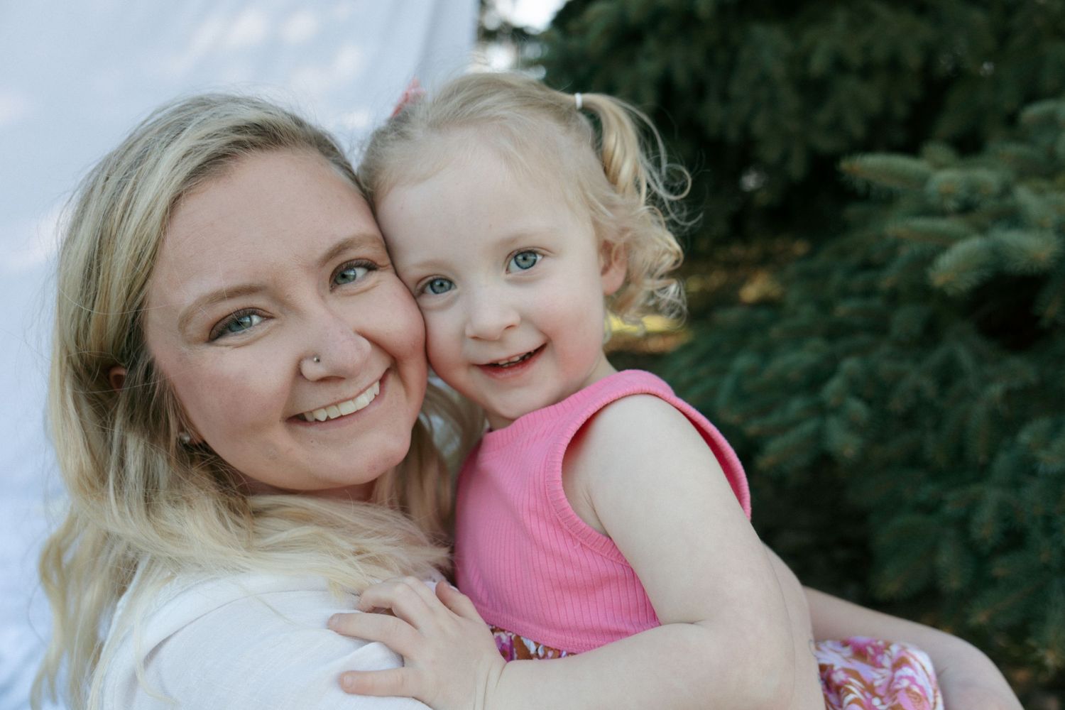 mom holding baby girl smiling at camera cheek to cheek