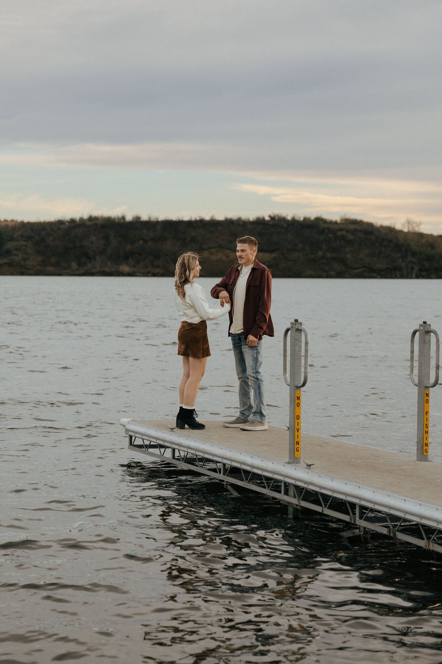 People share a moment together on a wooden dock extending into a peaceful lake.