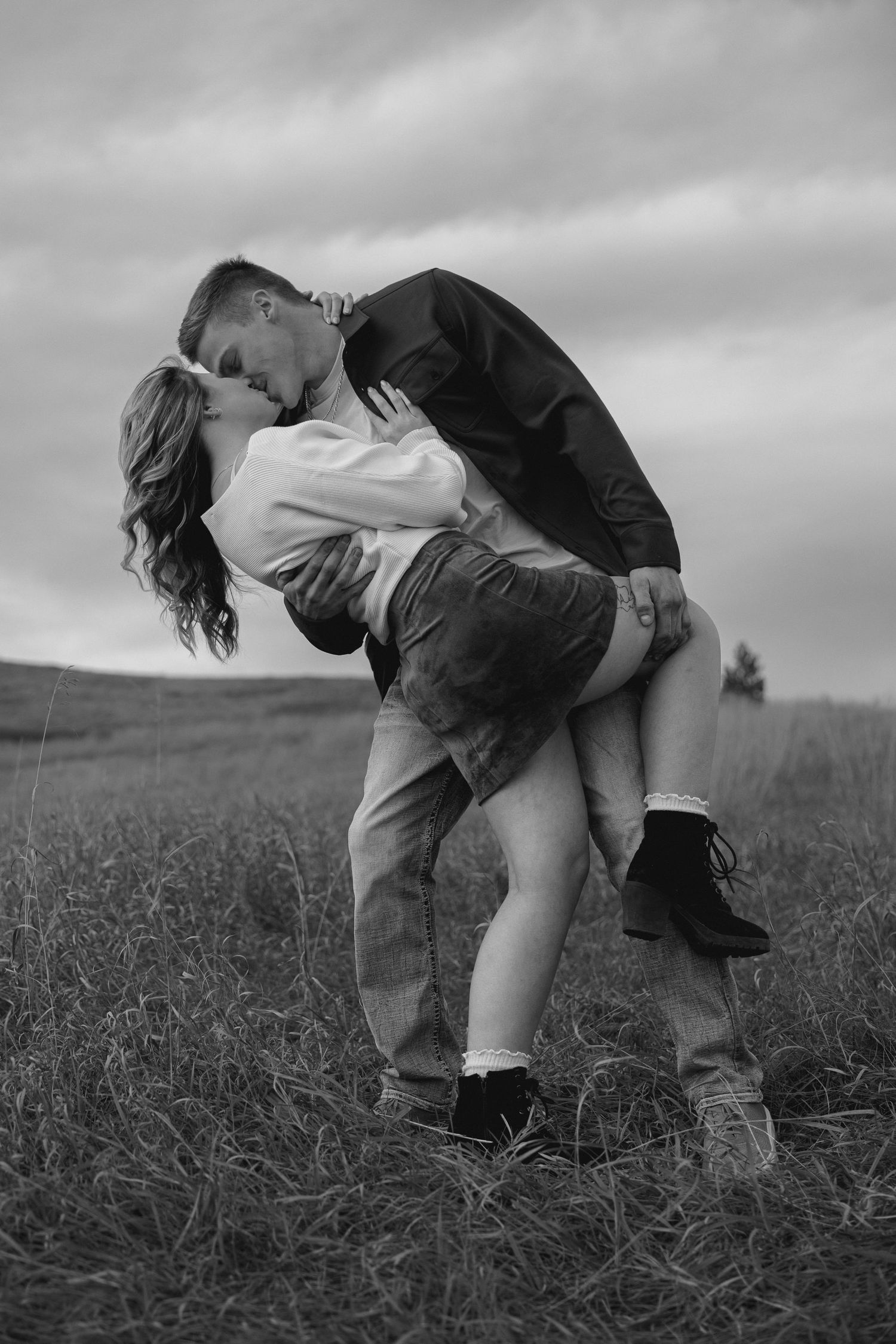 Black and white romantic portrait in dramatic dip pose on hillside.