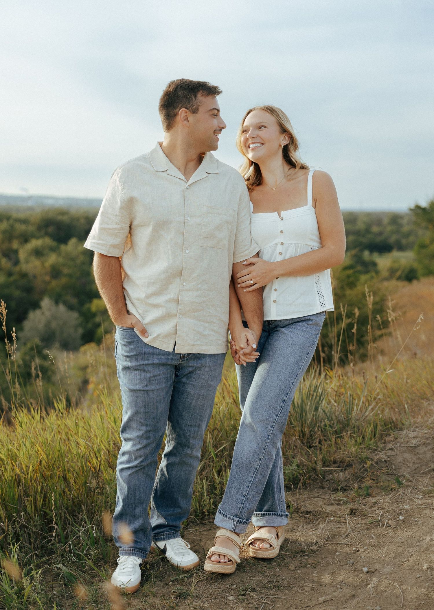 A couple in coordinated outfits shares a tender moment on a nature path.