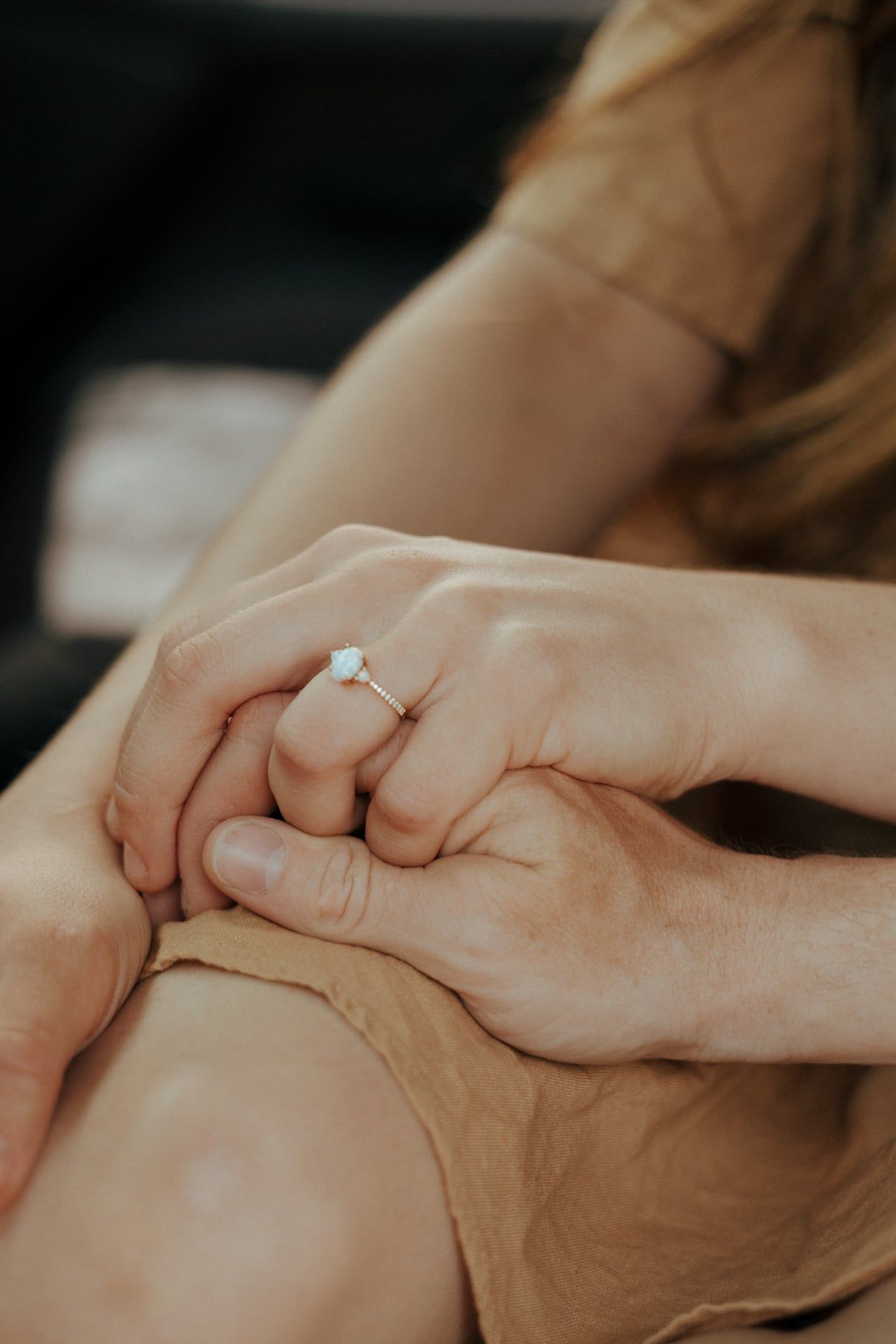 couple holding hands with engagement ring showing
