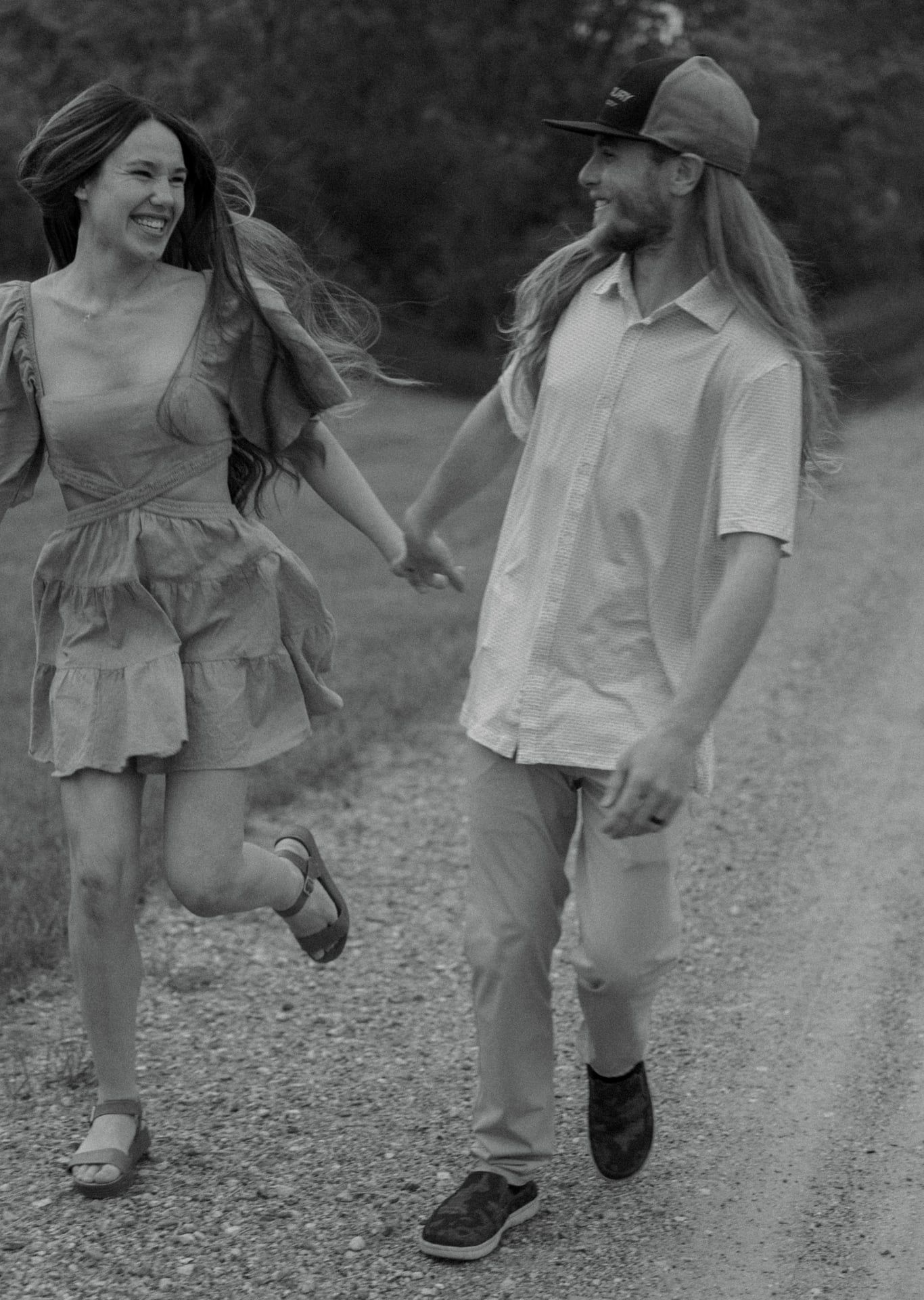 couple running on dirt road together laughing