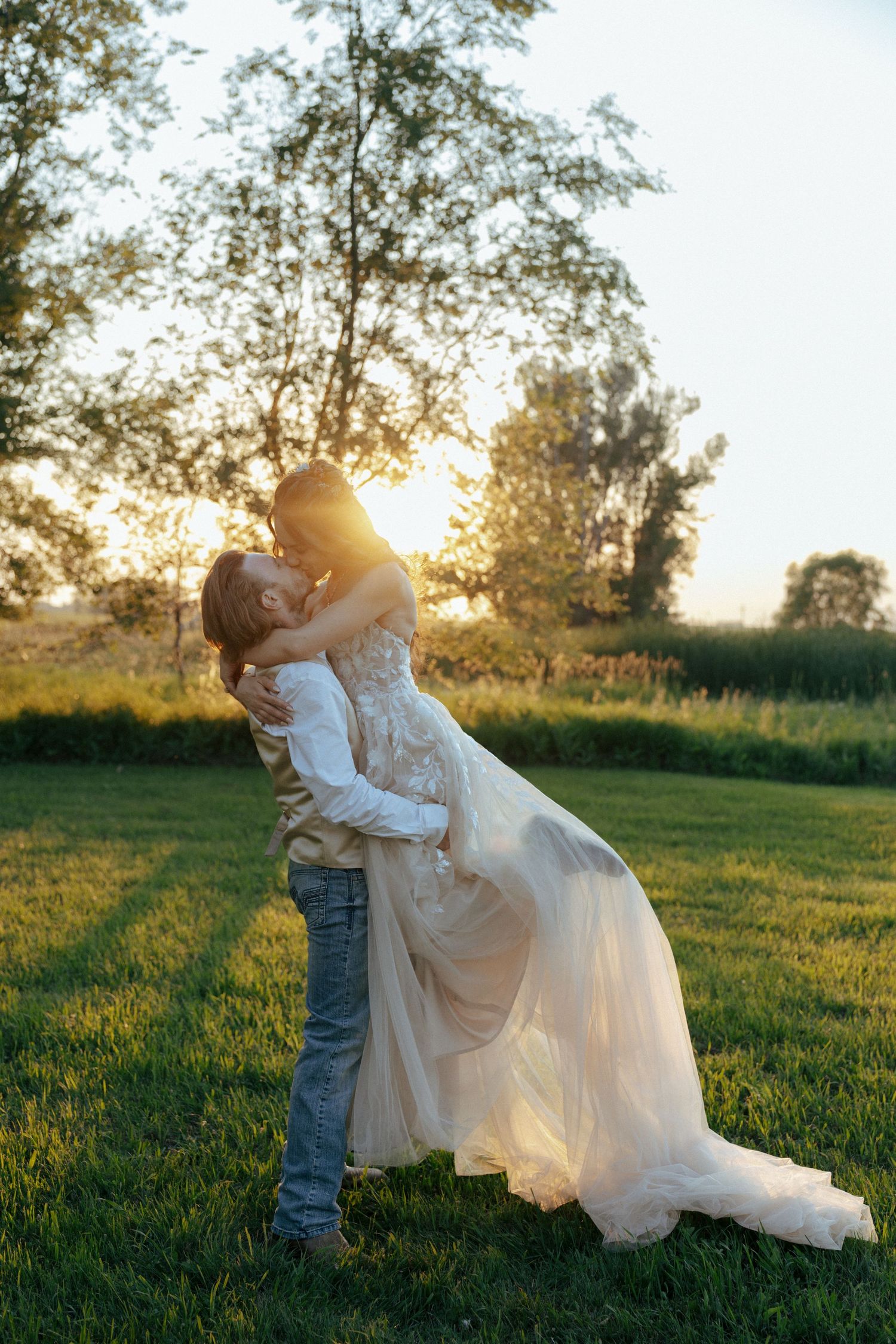 Romantic sunset wedding photos in a grassy field with golden hour lighting.