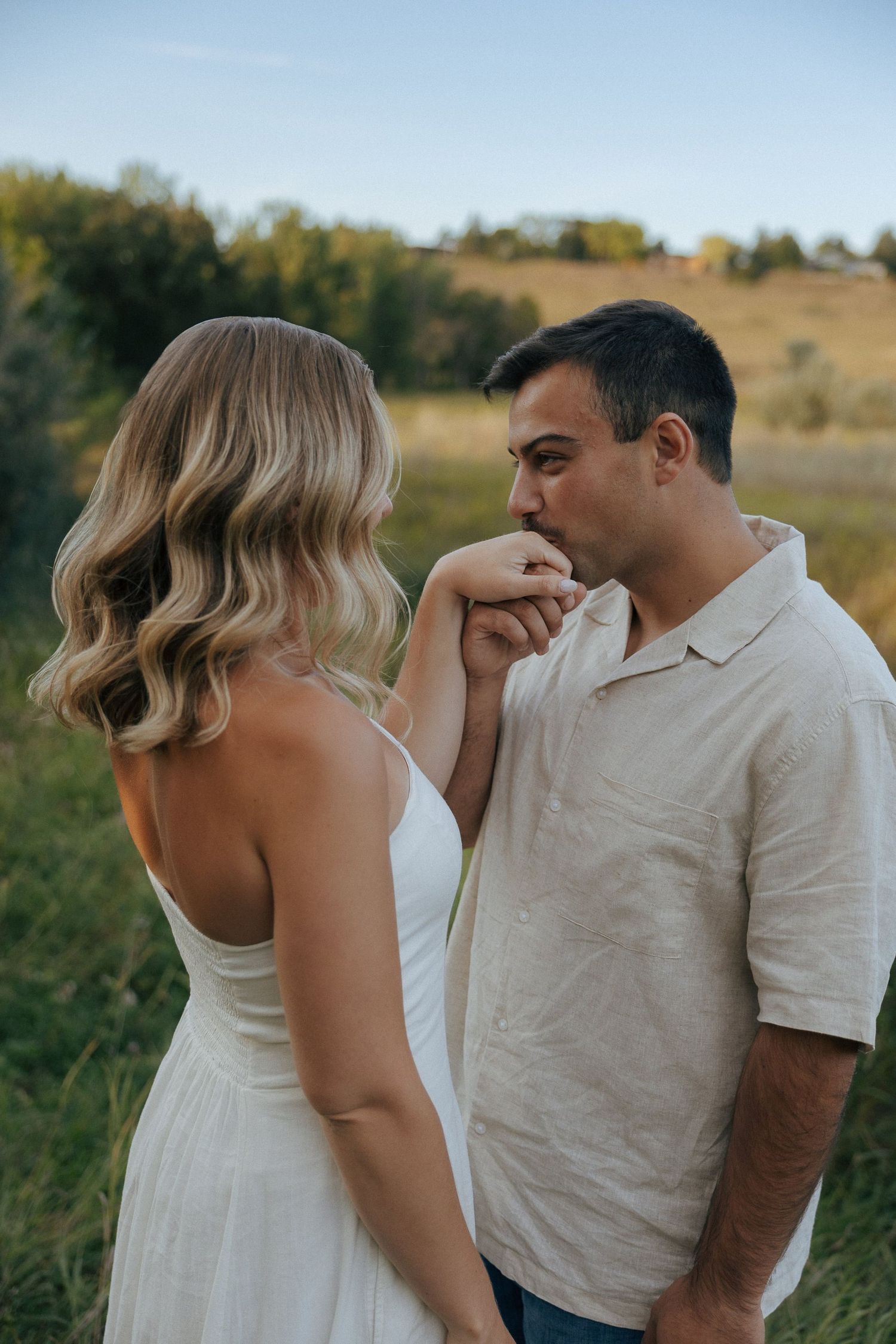 A sweet candid moment between a couple in a meadow during golden hour.