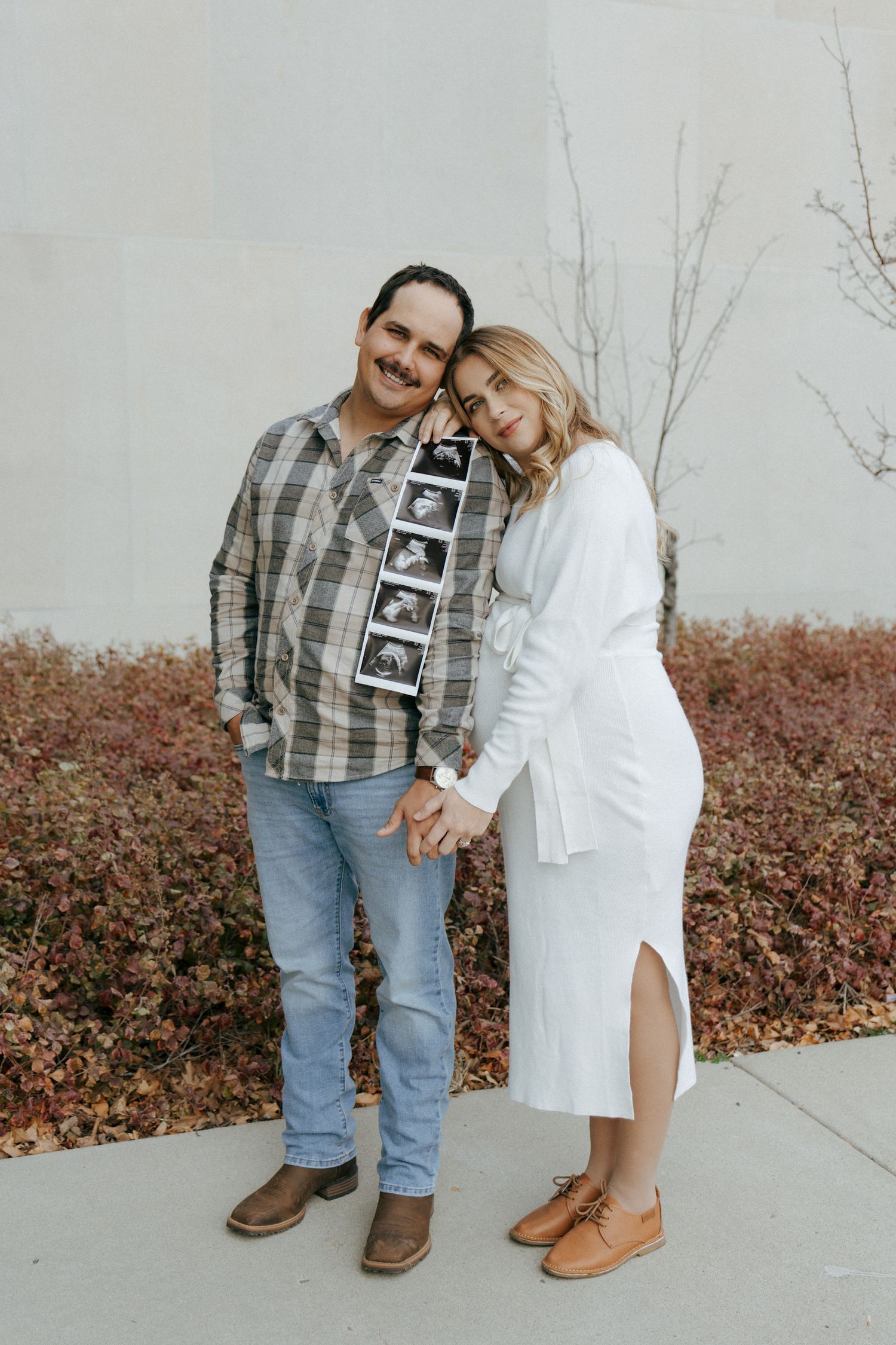 couple holding ultrasound photos in front of Heritage Center in Bismarck