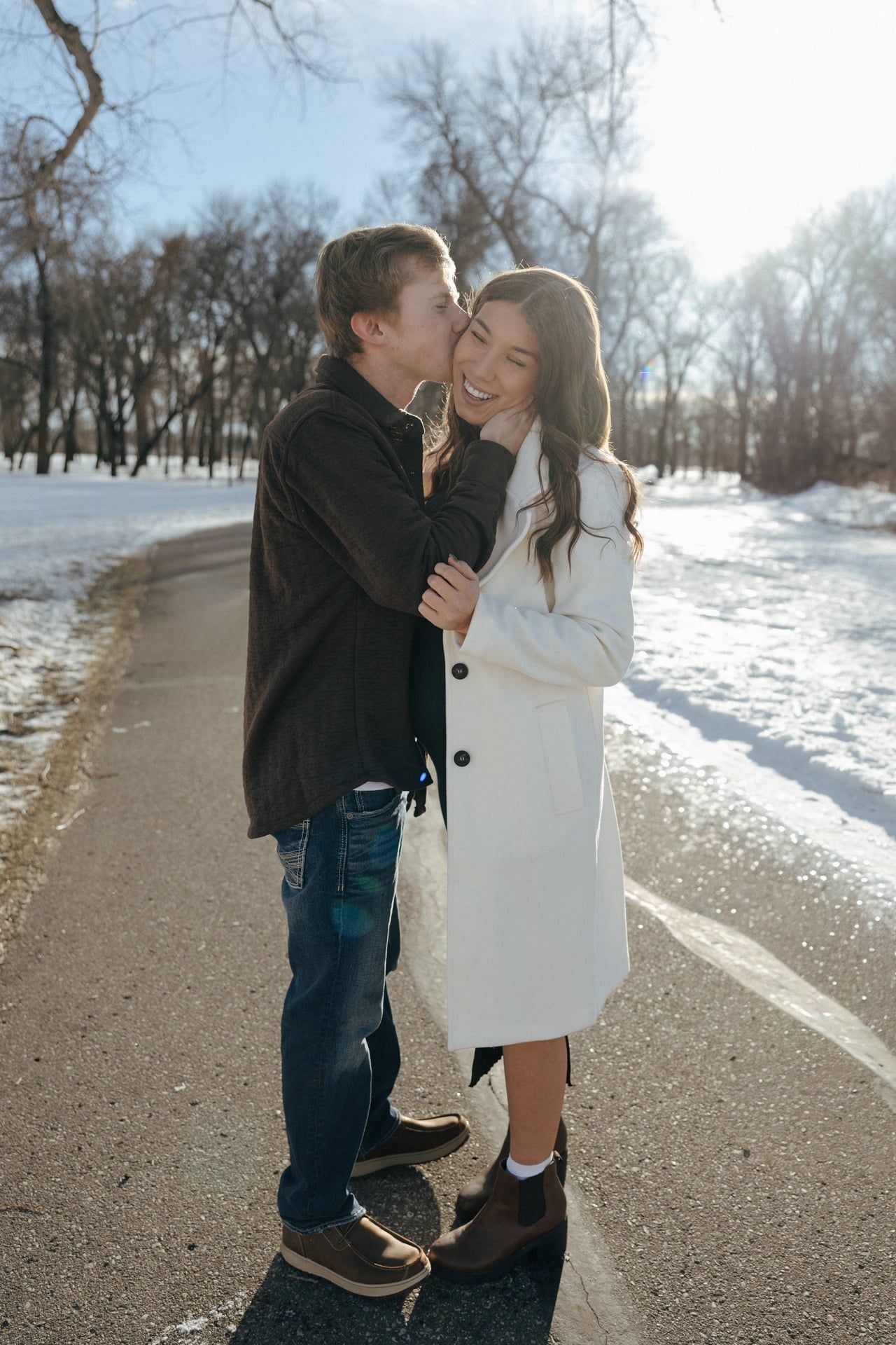 Couple kissing in snowy park in Bismarck