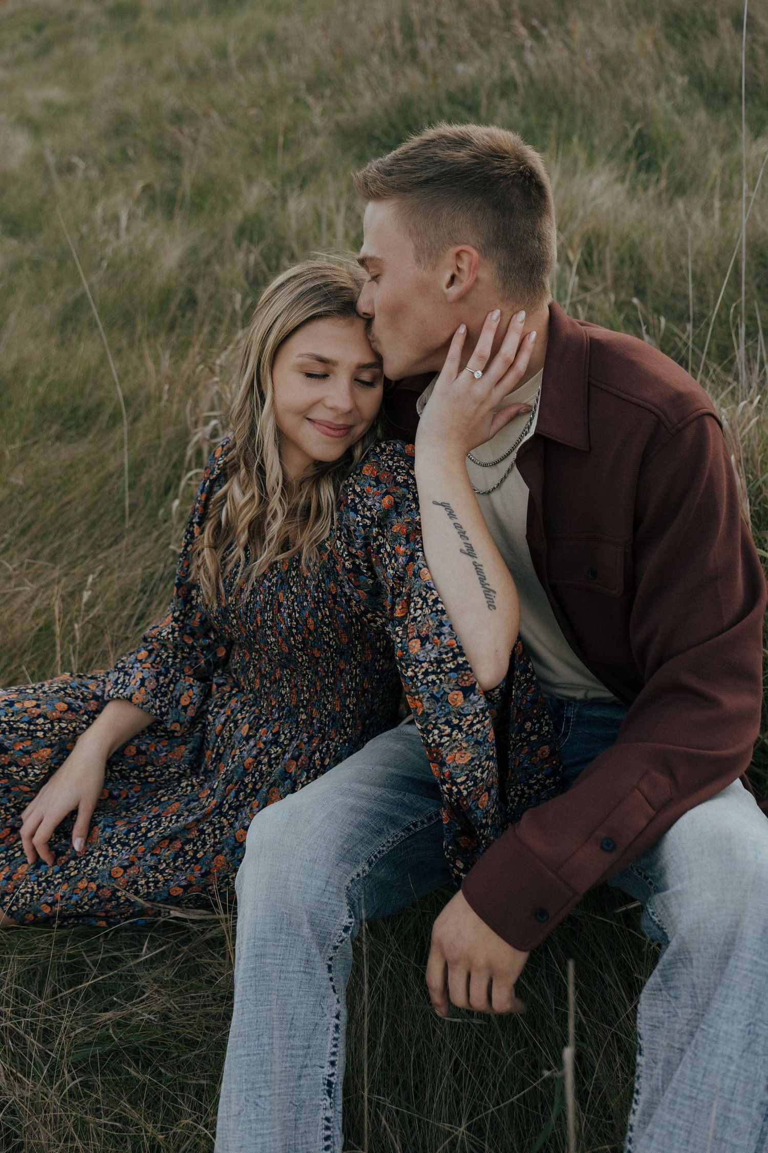 Intimate couple photoshoot showing tender moments on grassy slope.