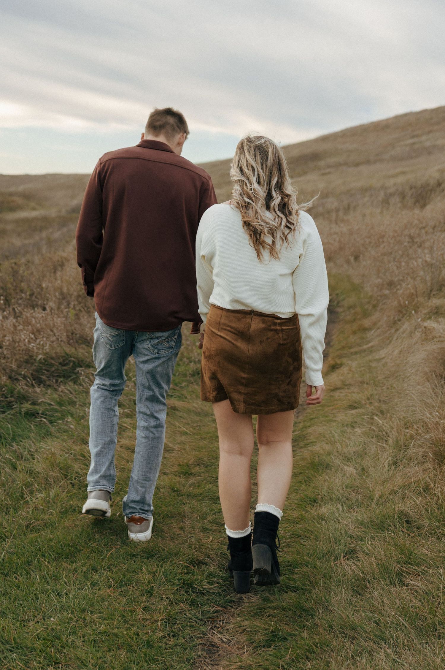 Couple walking together on hiking trail through autumn hillside.