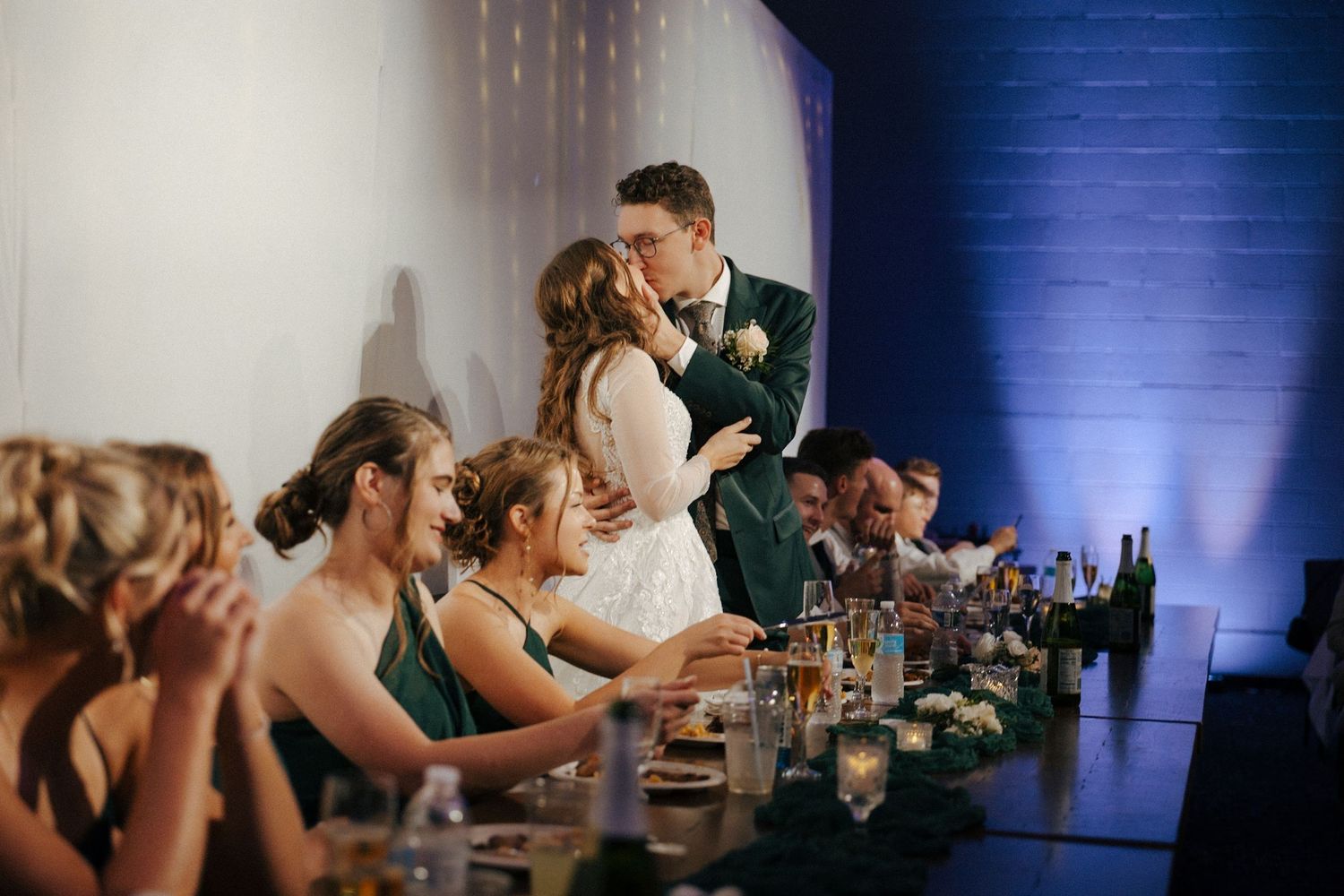 Wedding reception scene at head table with blue uplighting and decorative details.