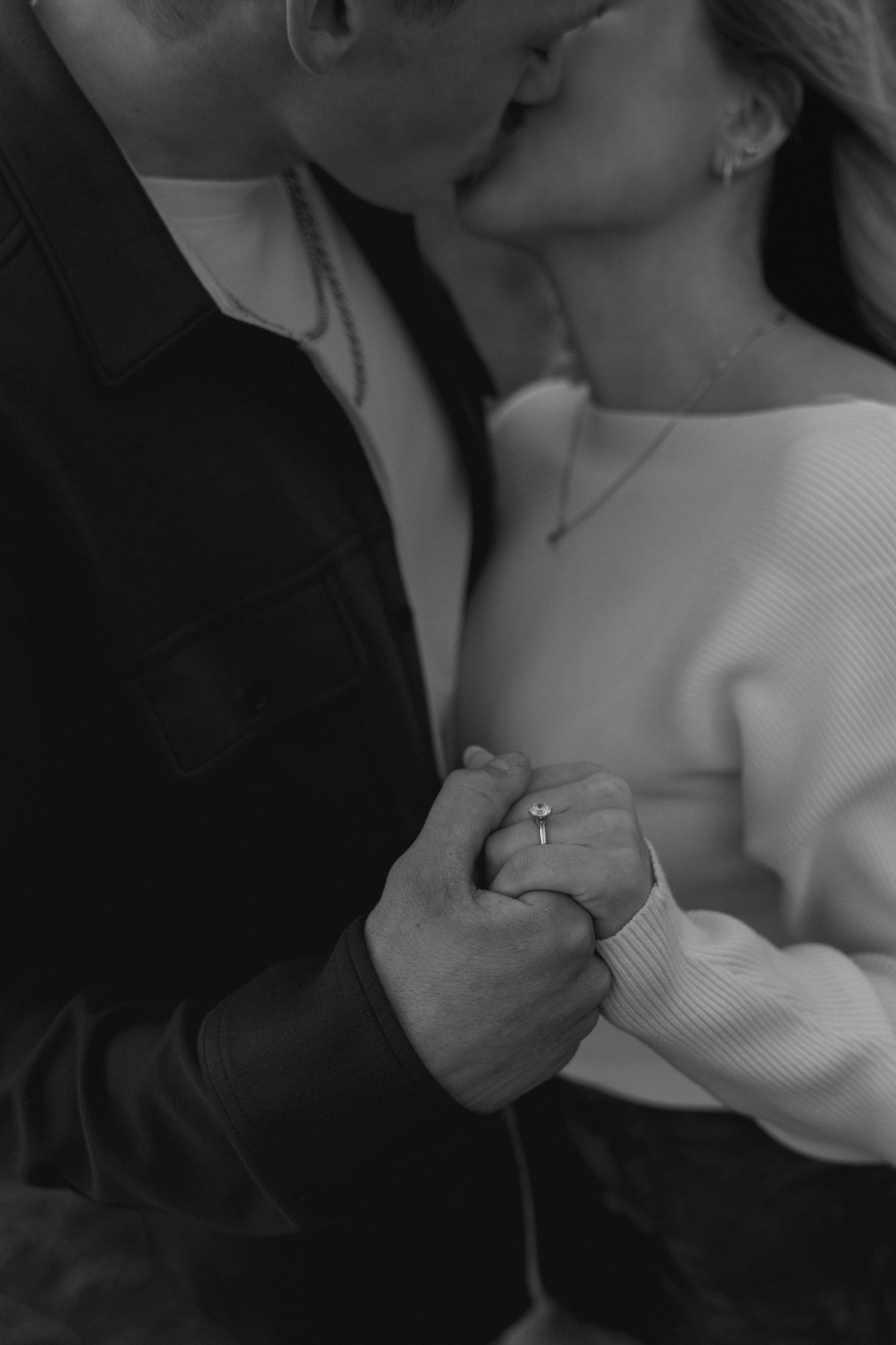 Close-up shot of a couple embracing in black and white with dramatic shadows.