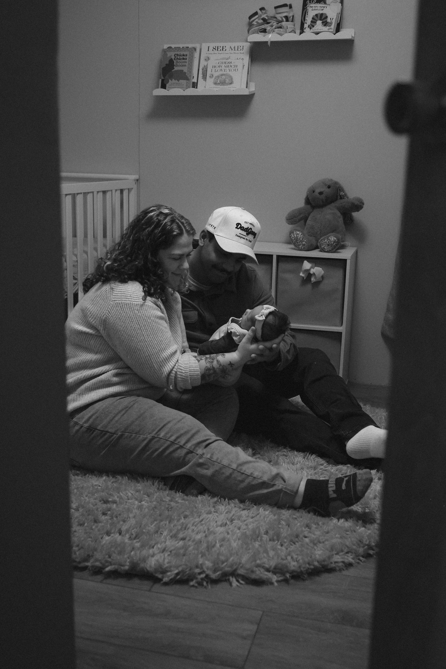 mom and dad looking down at newborn at home in nursery