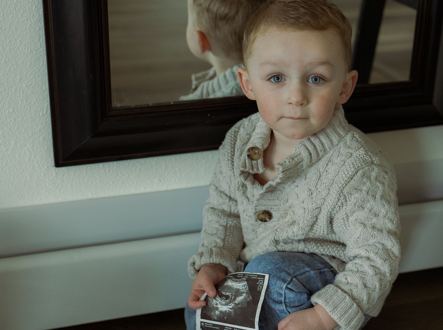 toddler holding ultrasound photos for at home maternity session