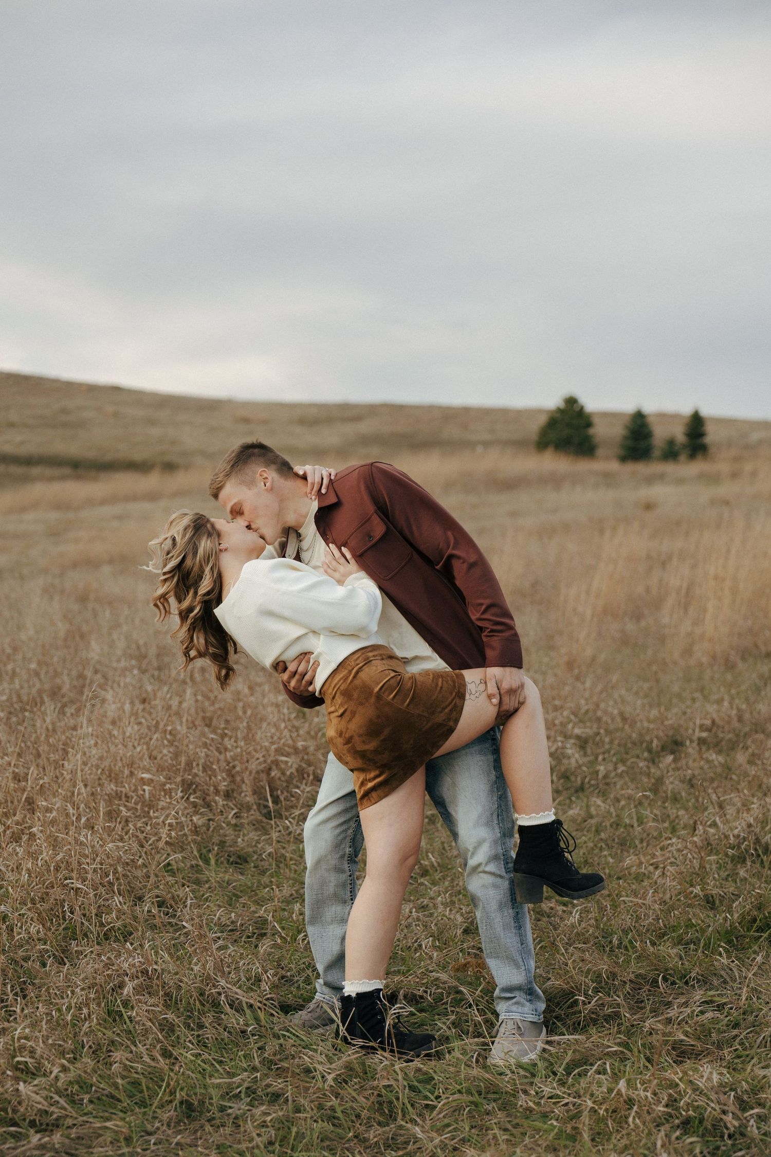 Intimate moment captured in golden field with mountains in background.