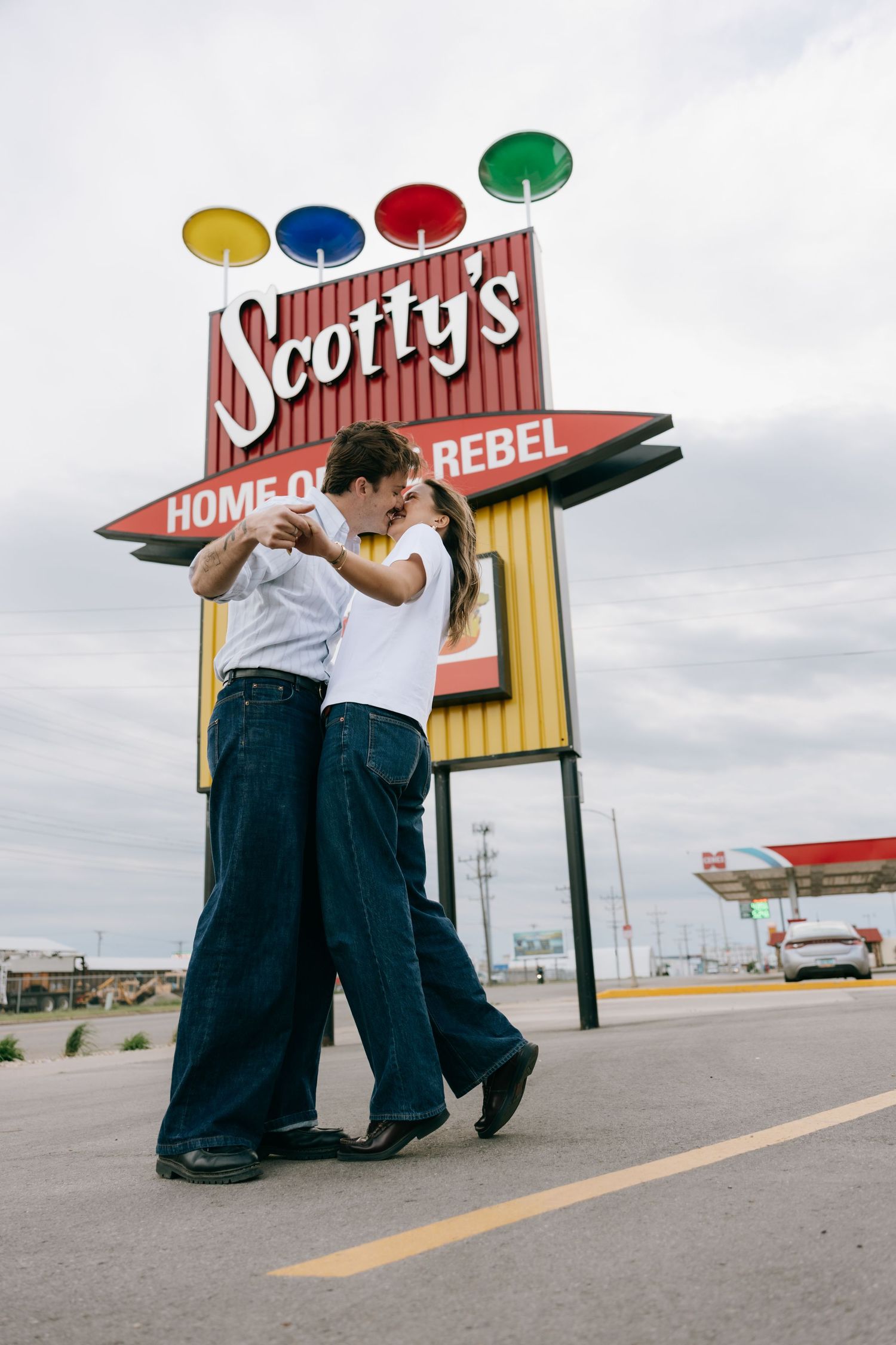 Couple dancing romantically in front of Scotty's Home of the Rebel retro diner sign in a parking lot.