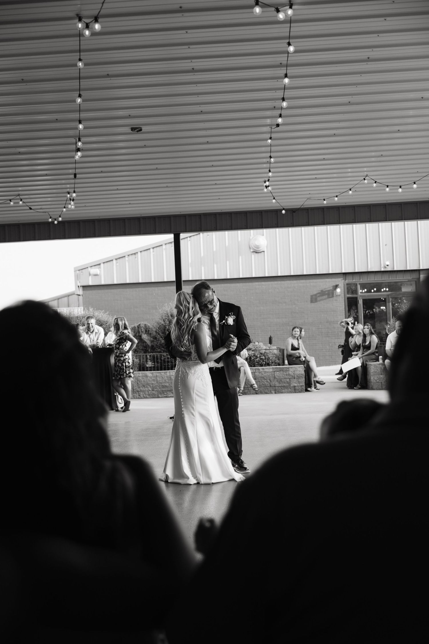 Black and white photo of a bride and groom sharing their first dance at an outdoor wedding reception.