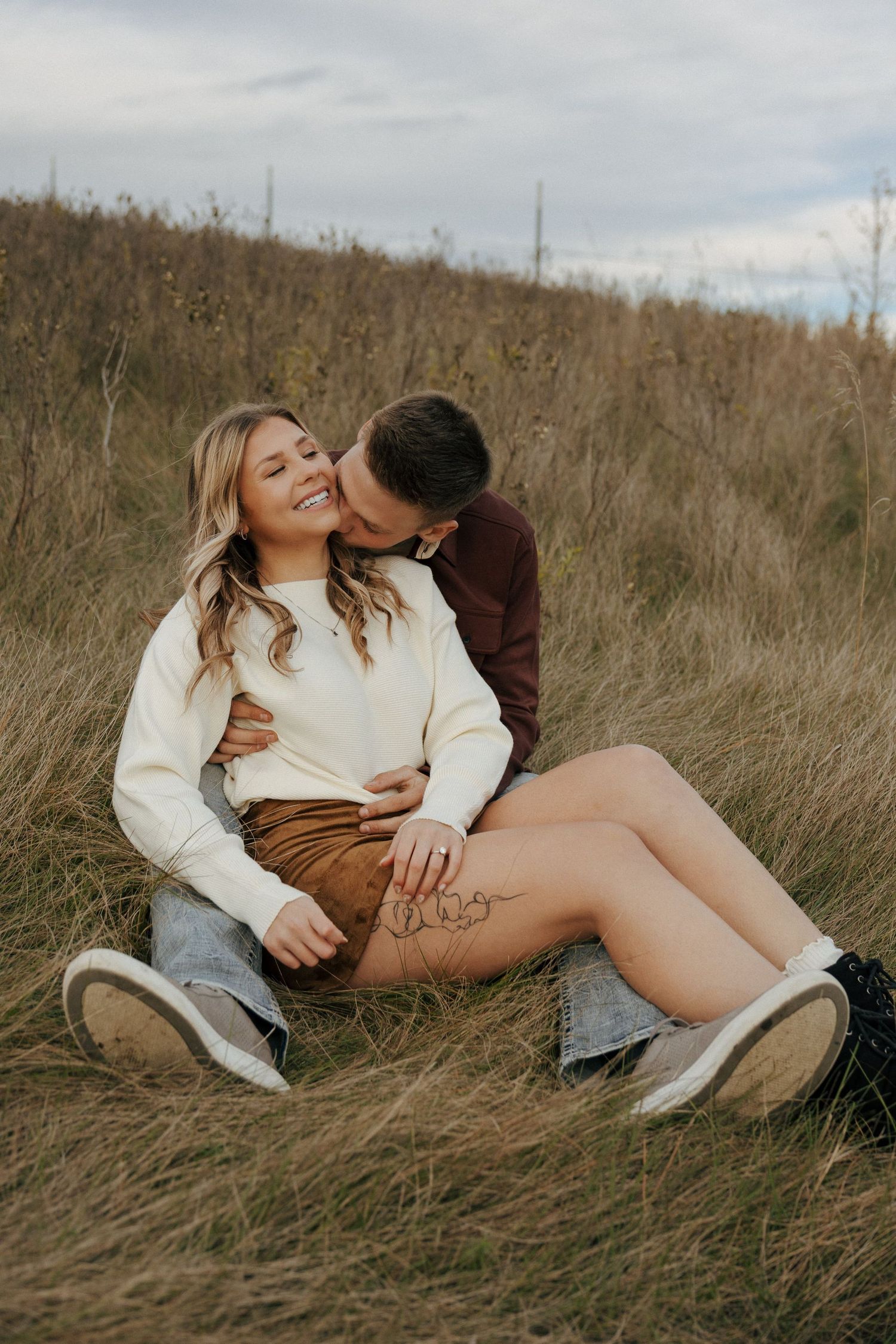Intimate portrait of couple laying in hillside grass during autumn.