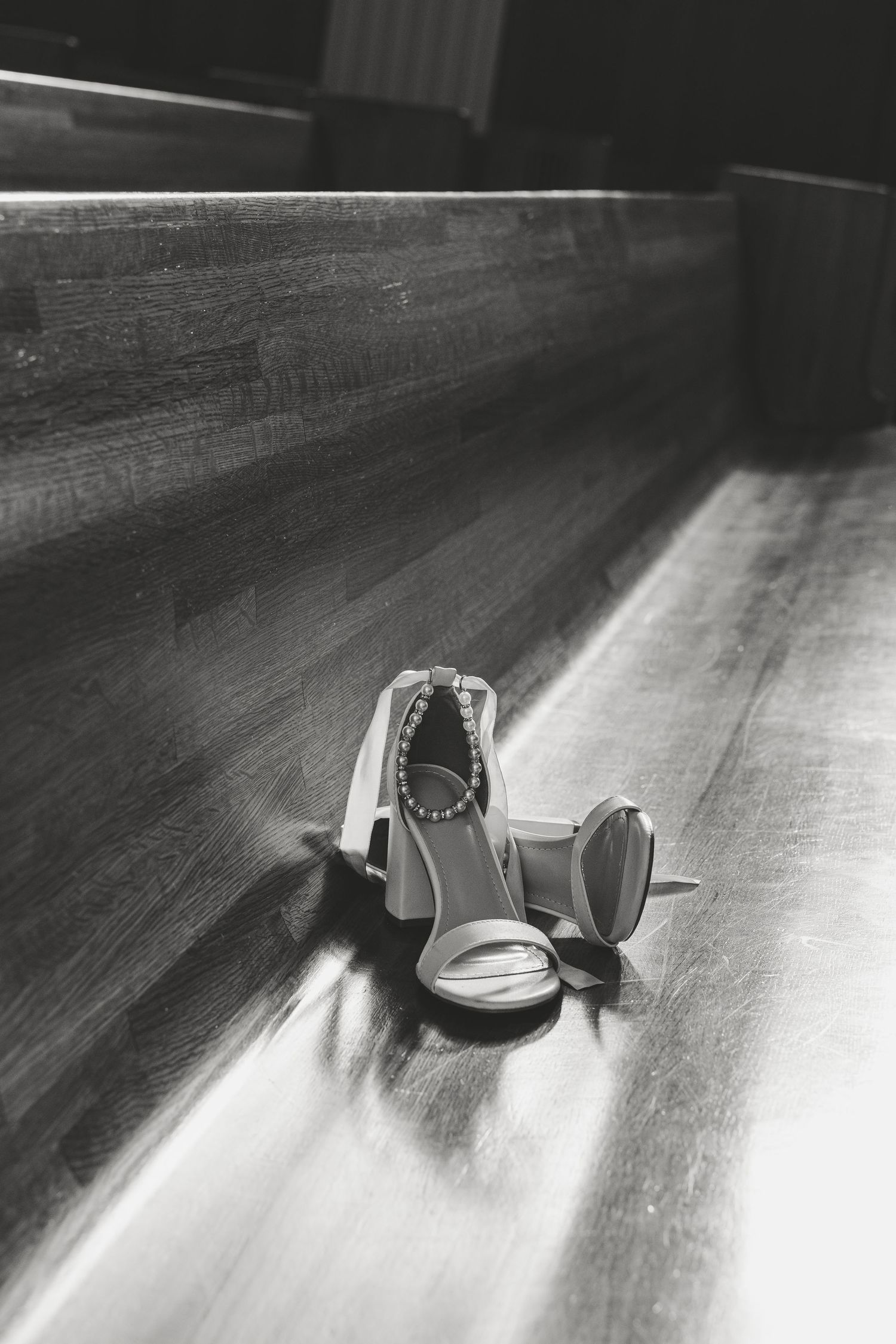 Wedding rings casting shadows on a wooden surface in black and white.