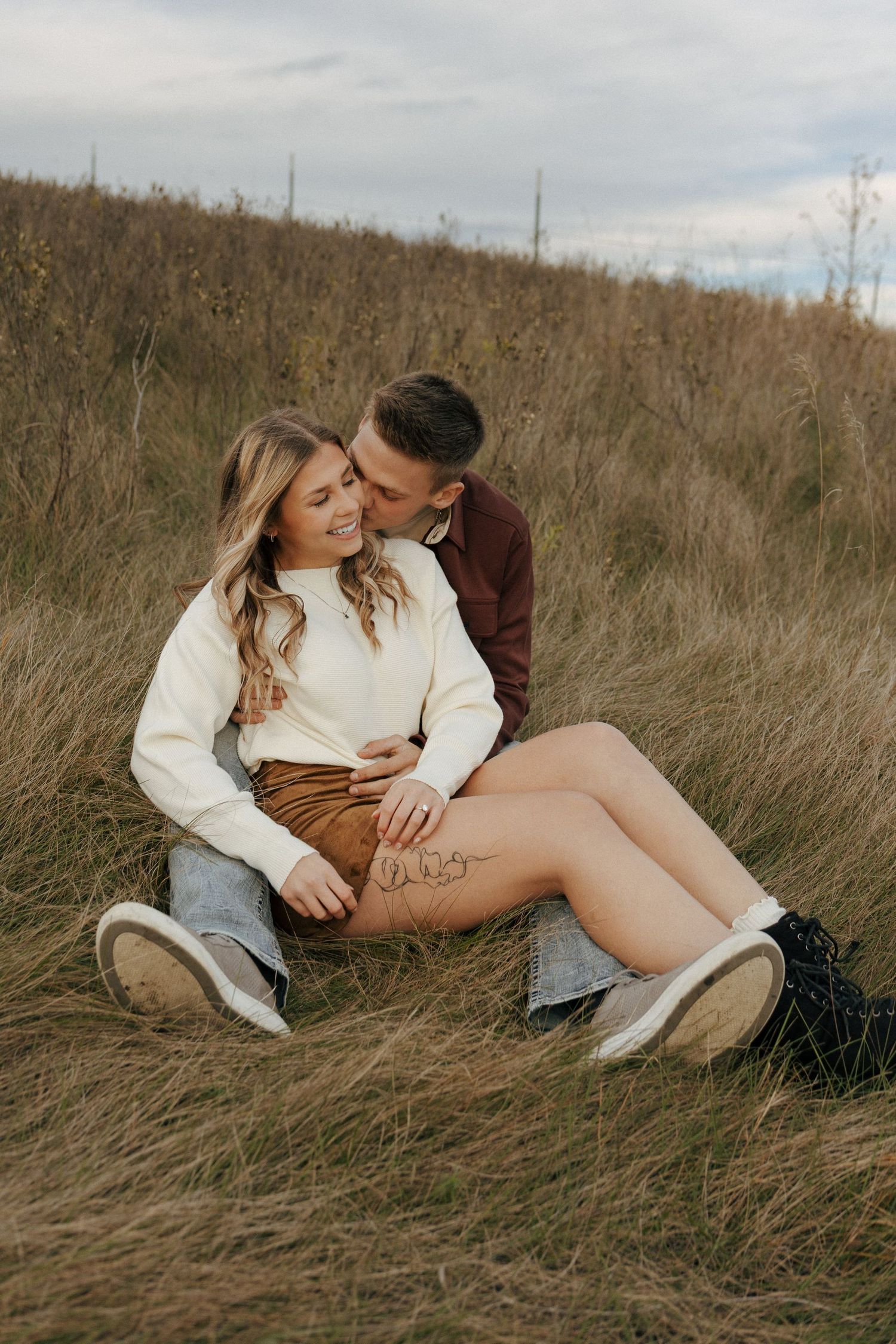 Couple relaxing in autumn grass field during cloudy day.