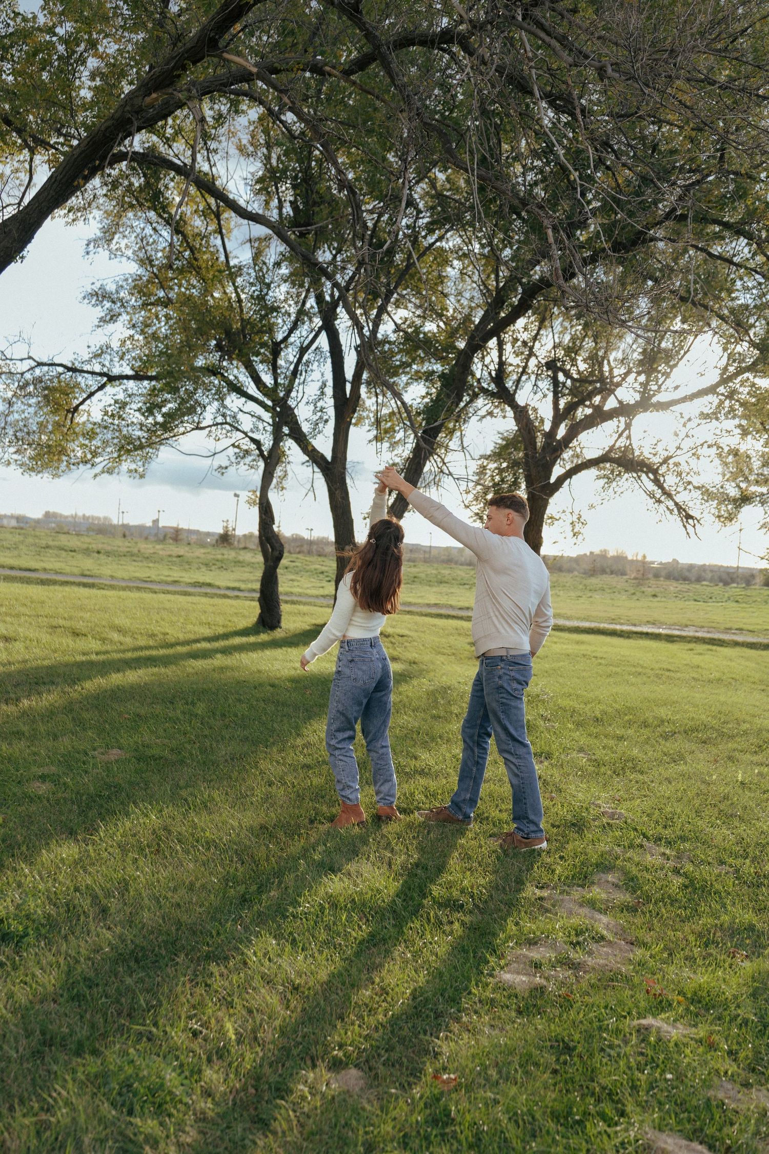 couple dancing together in grassy field for engagement photos