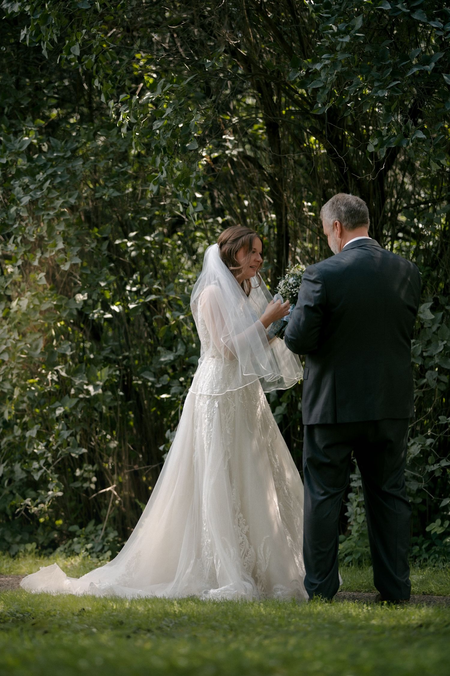Wedding couple exchanging vows in a lush garden setting surrounded by greenery.