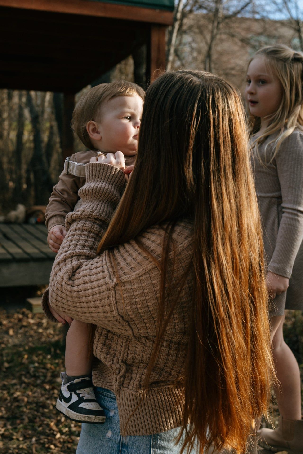 mom holding baby in arms with daughter behind them