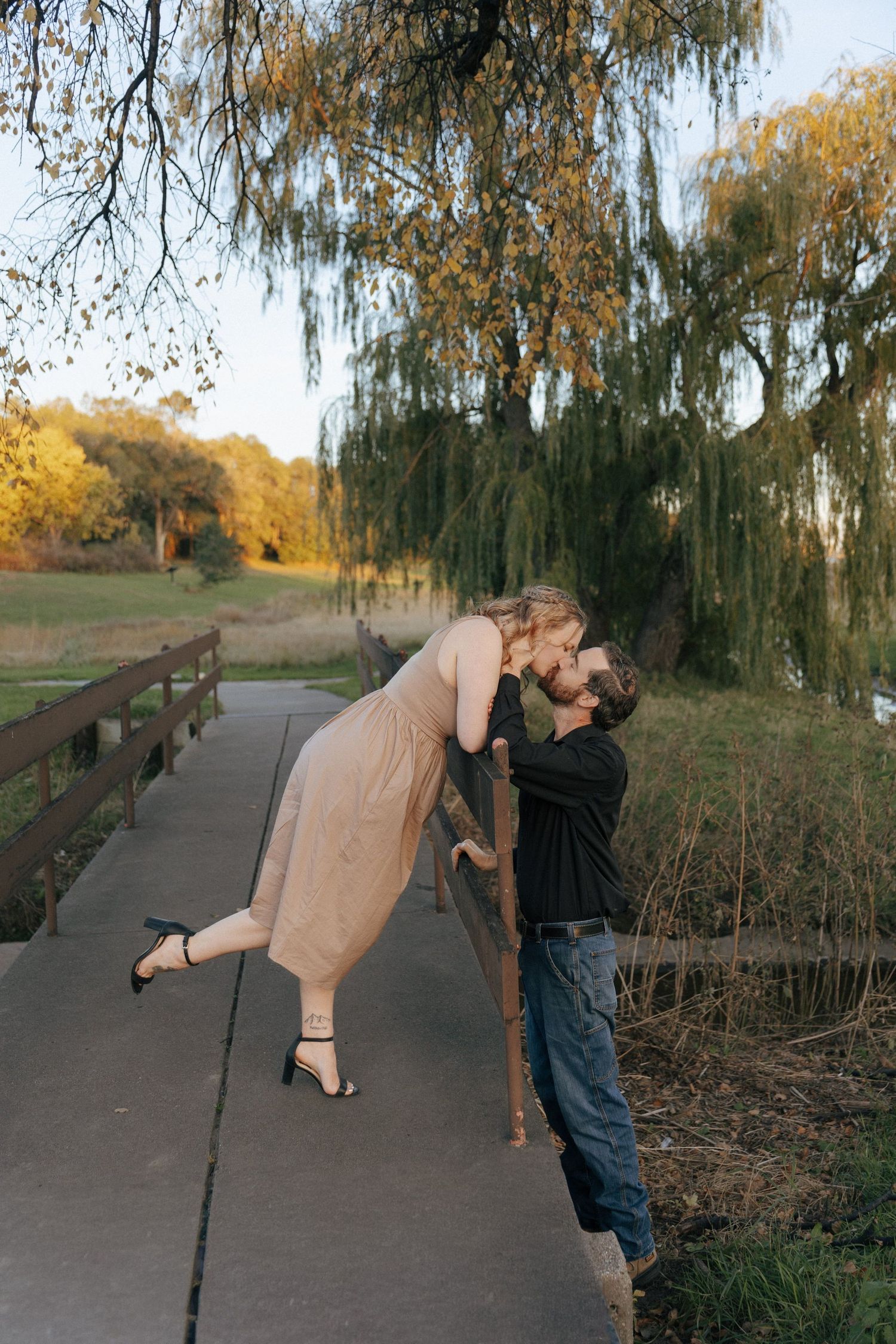 couple kissing with weeping willow in back for engagement photos