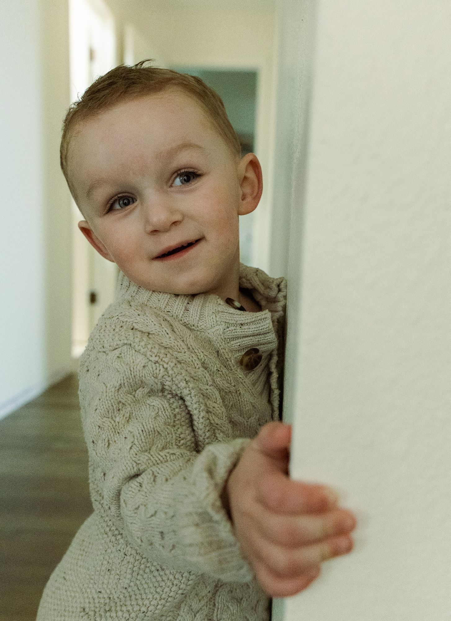 toddler peaking around the corner for maternity session at home