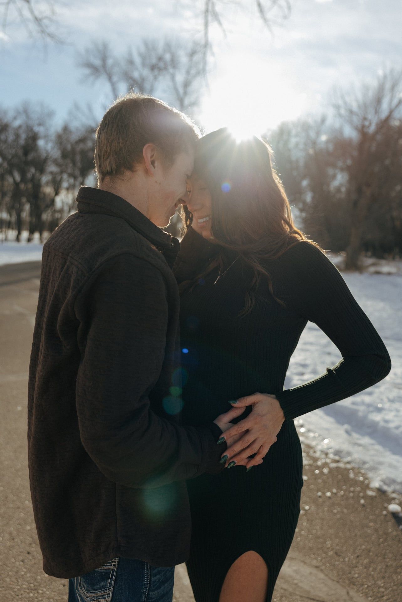 sunlight peaking through couple embracing during maternity session in Bismarck