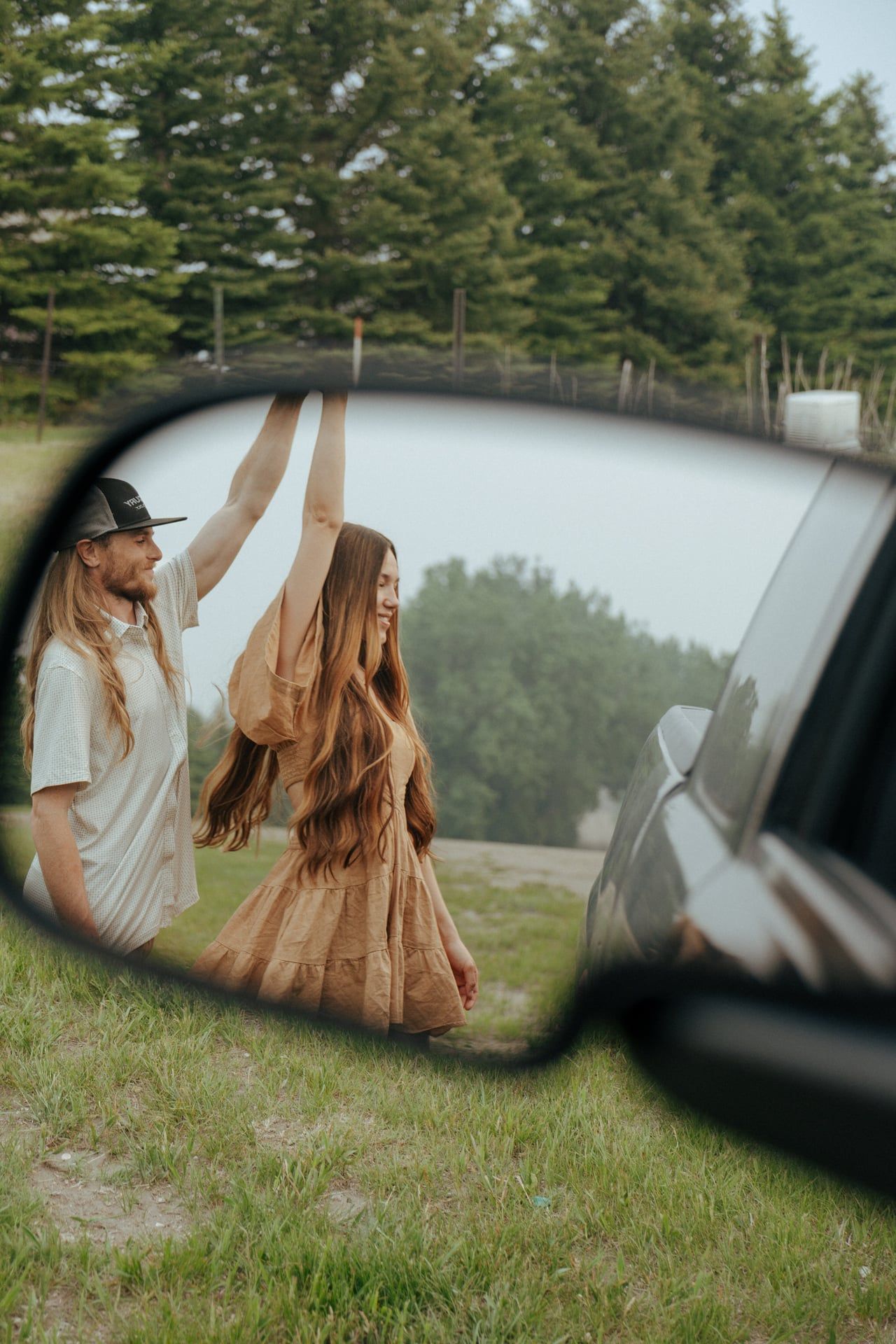 couple in reflection of truck mirror dancing and girl getting spun under his arm